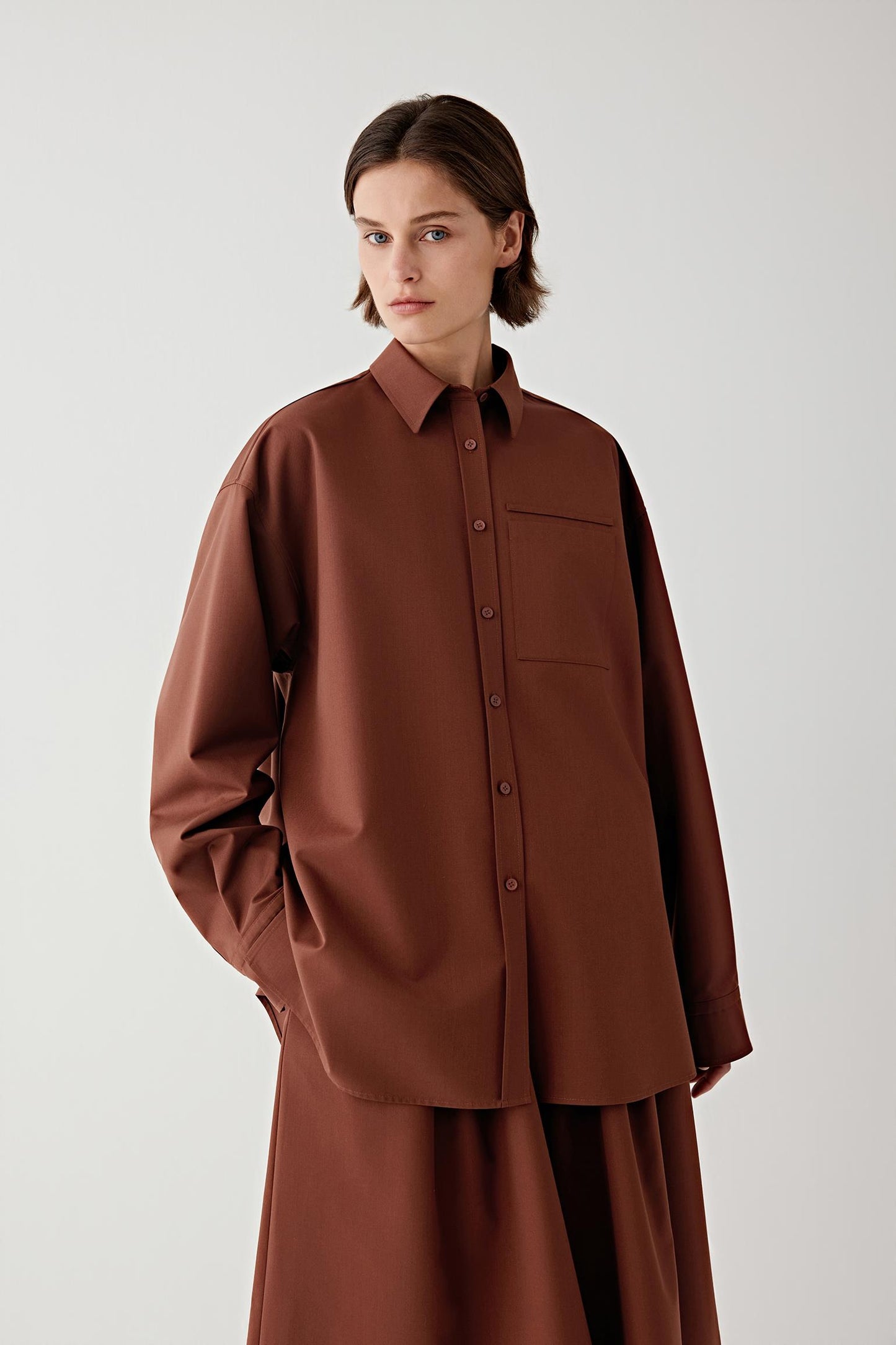 Person wearing a brown shirt on a plain background