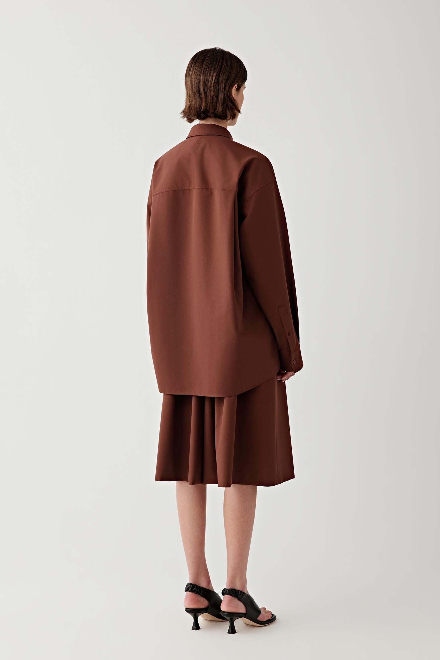 Person wearing a brown shirt and skirt set on a white background