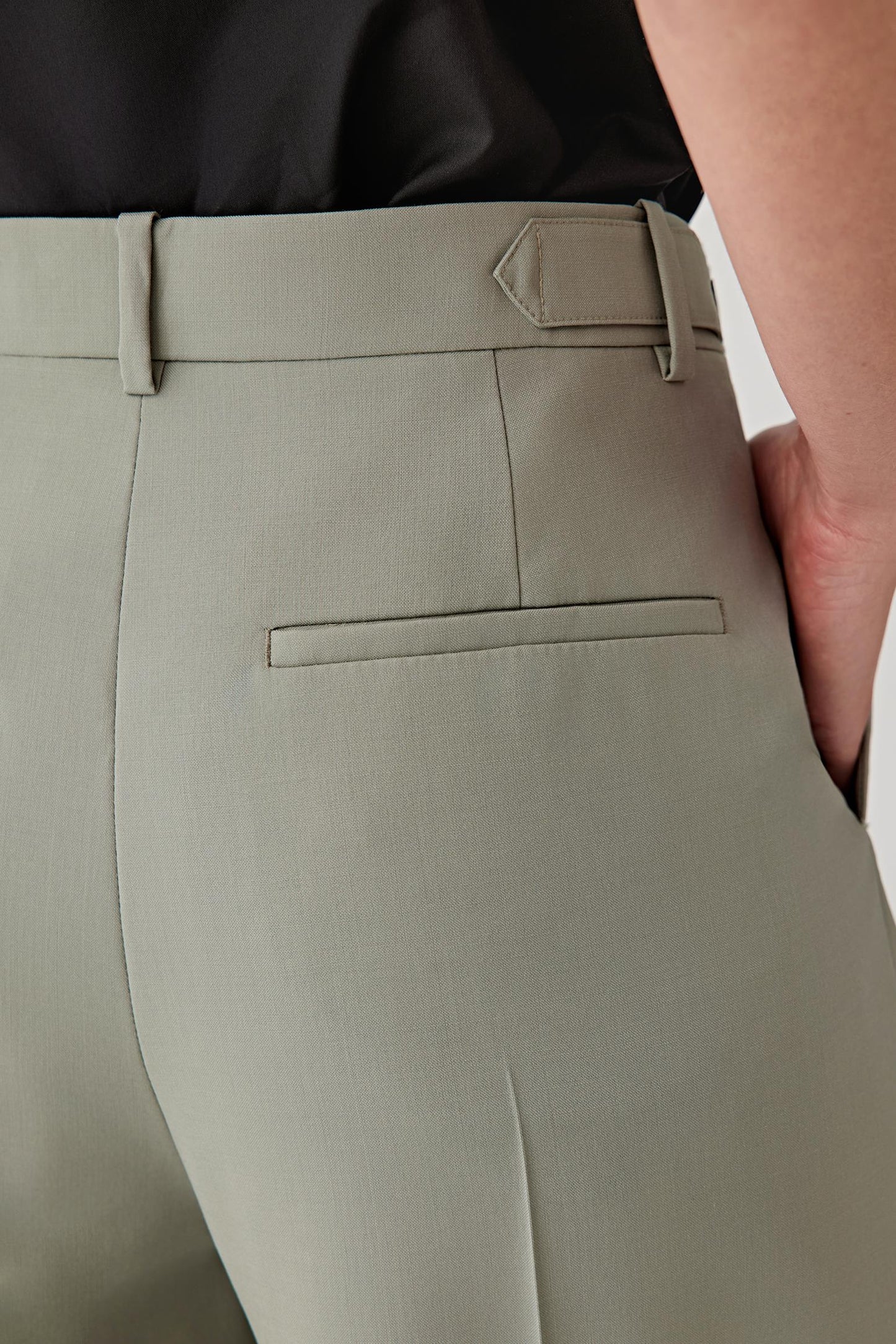 Close-up of light gray pants with a belt and part of a black shirt visible.