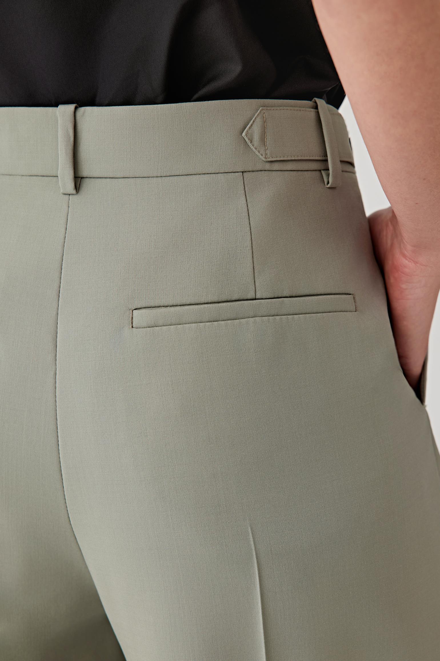 Close-up of light gray pants with a belt and part of a black shirt visible.