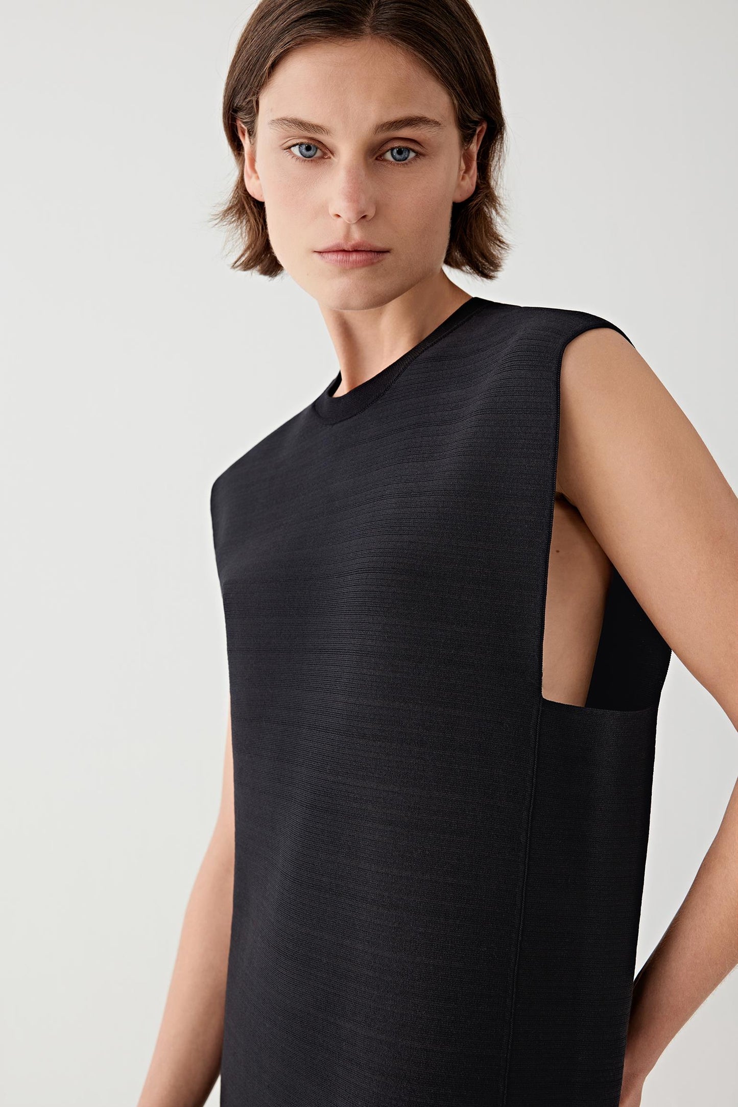 Woman wearing a black sleeveless top against a light background