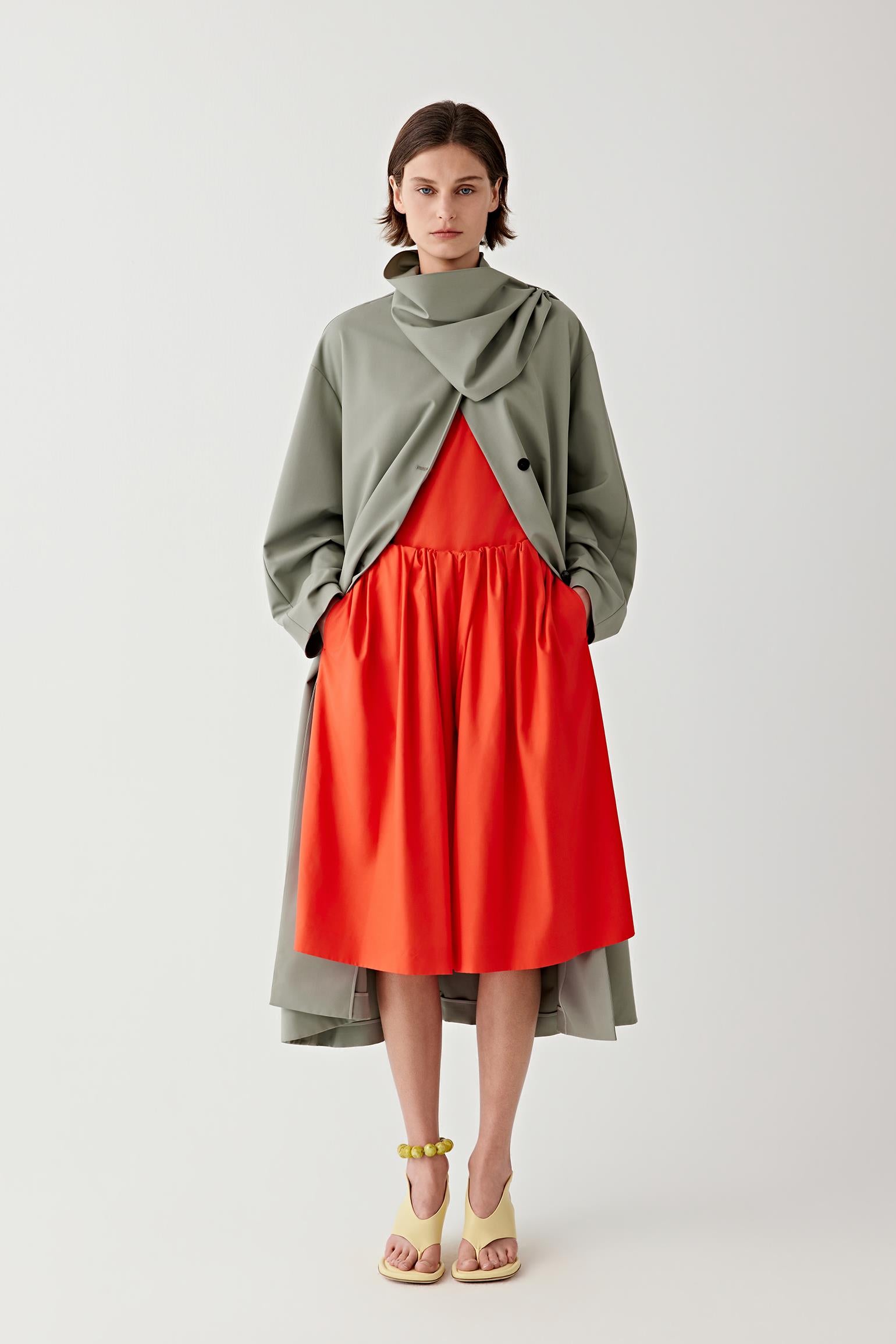 Front view of a woman wearing red shorts in spun silk poplin, highlighting the smooth compact surface, fluid drape and soft sheen of the fabric. The vivid red shade emphasizes the clean structure and lightweight movement of the silk poplin.