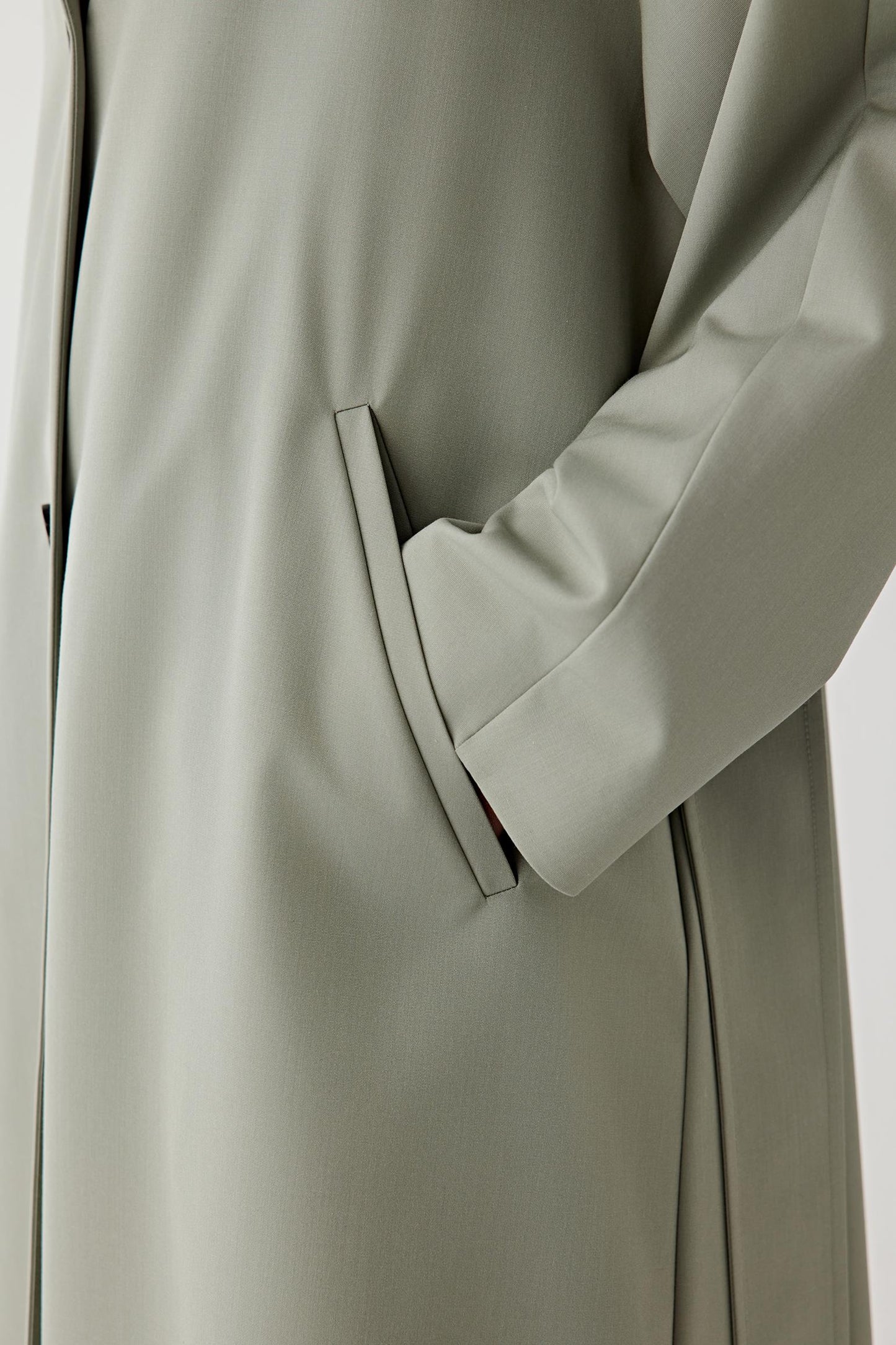 Close-up of a light olive green coat with a white background
