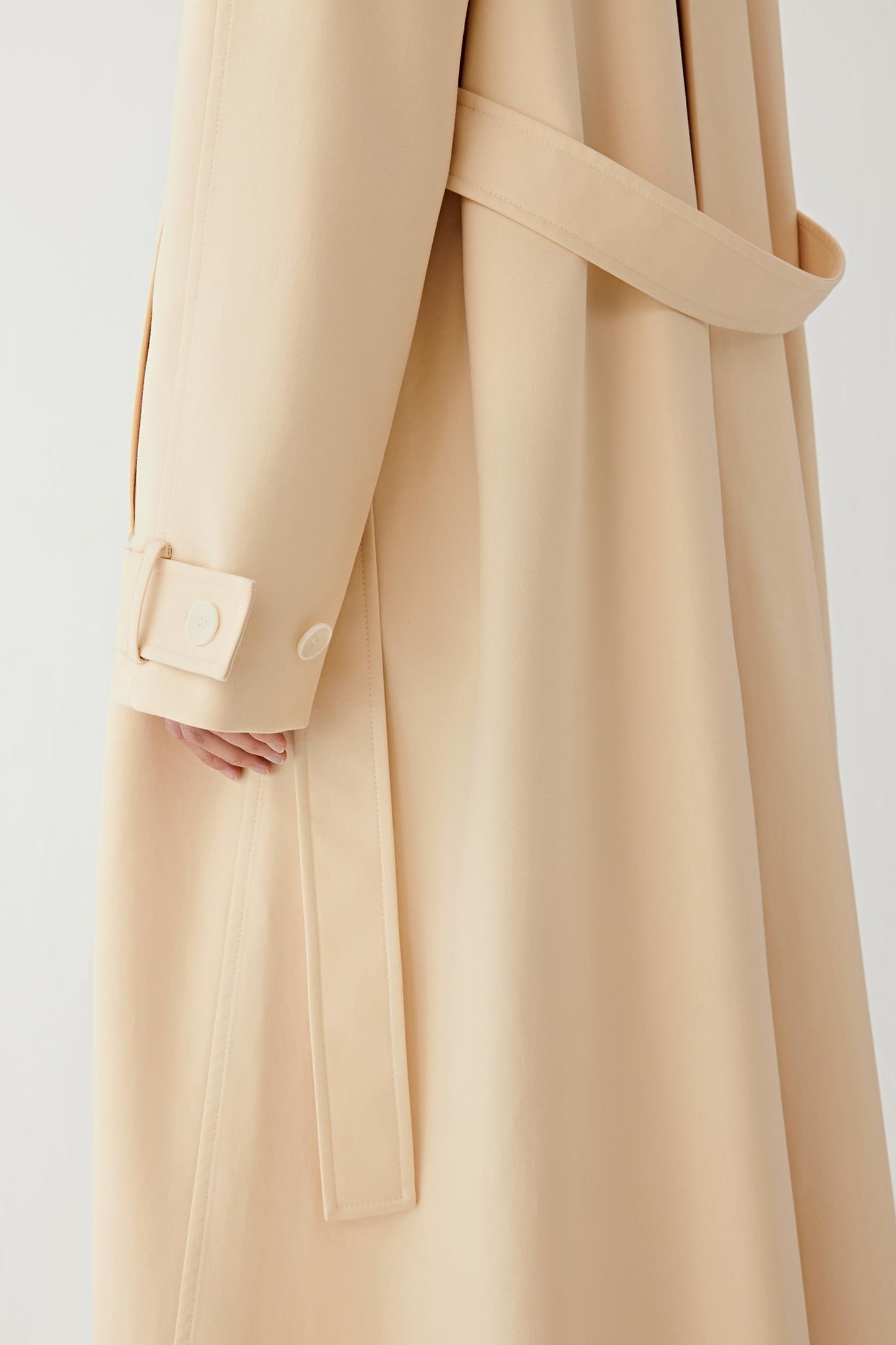 Beige trench coat with a belt on a white background