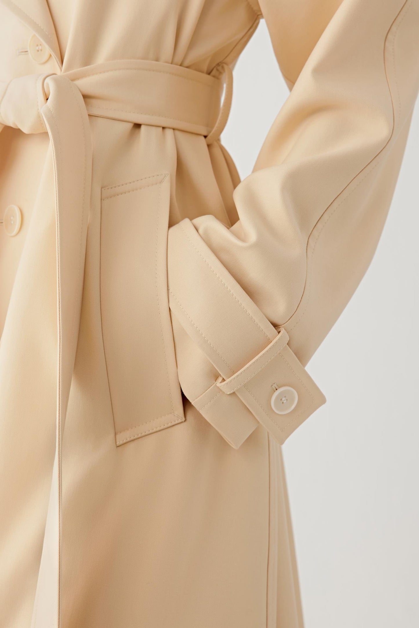 Beige trench coat with a belt on a light background