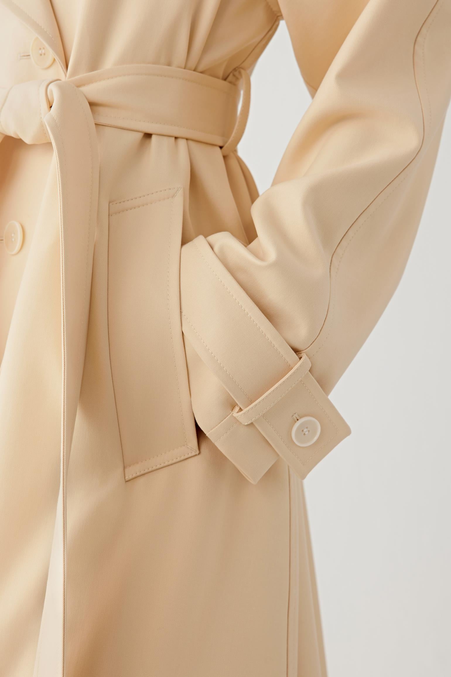 Beige trench coat with a belt on a light background