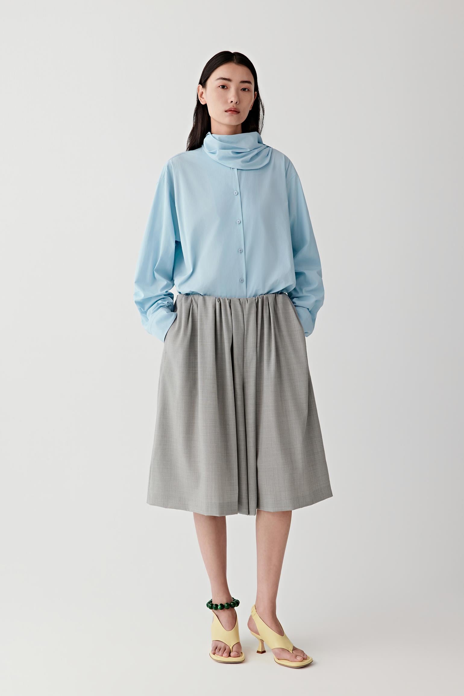 Woman wearing a light blue shirt and gray short on a white background