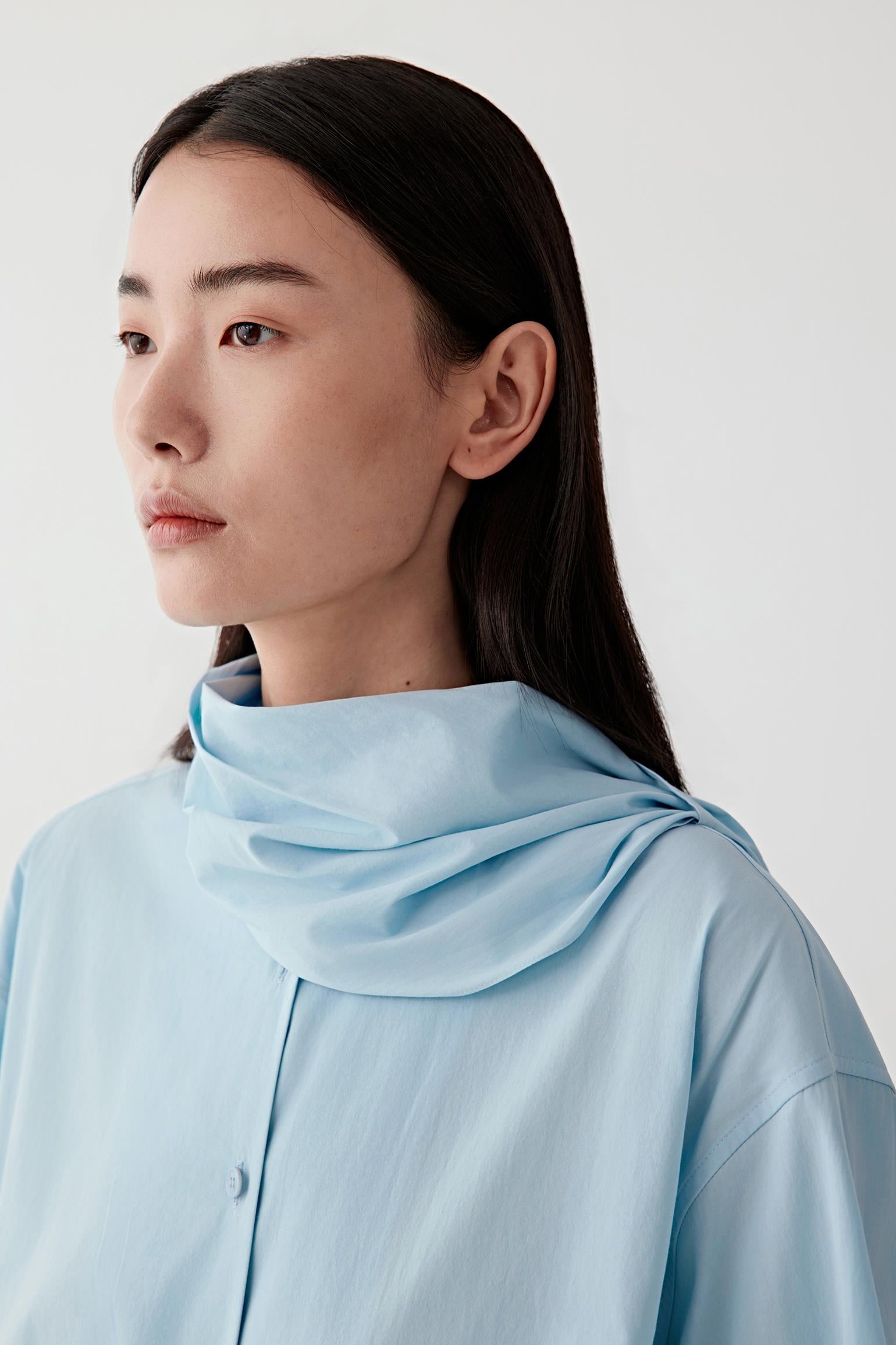 Woman wearing a light blue shirt against a white background