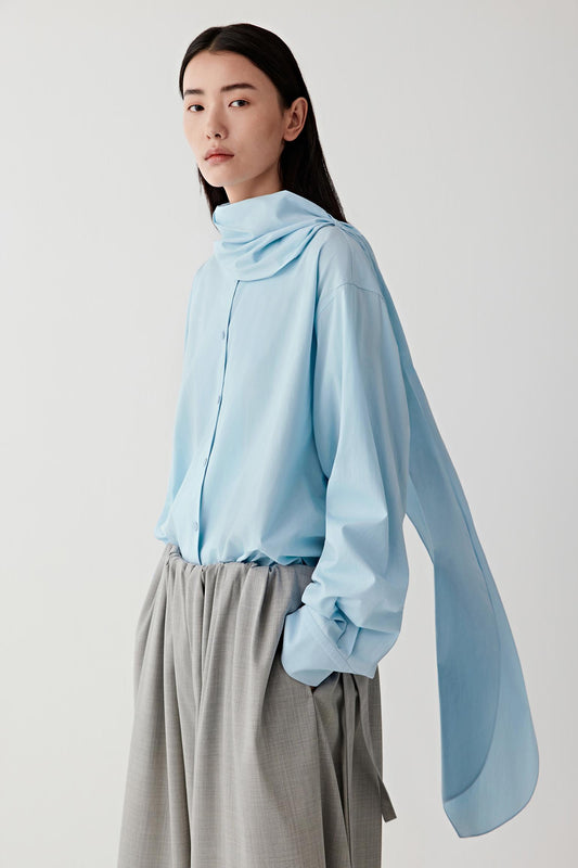 Person wearing a light blue blouse and gray short on a white background