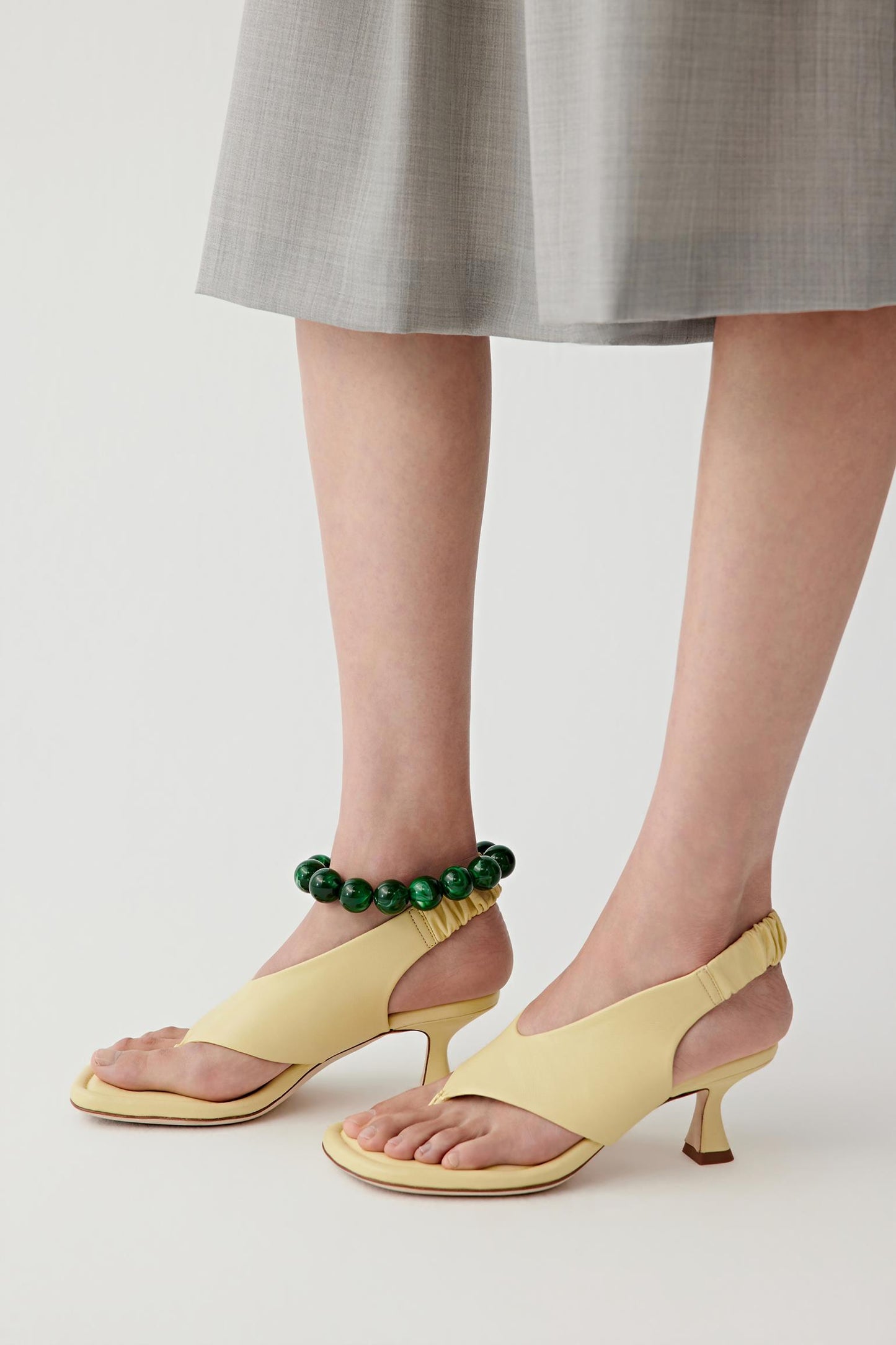 Three-quarter rear view focusing on the heel and back of the sandal, showing the slingback construction, heel shape and how the sandal sits on the foot while maintaining a clean, structured line