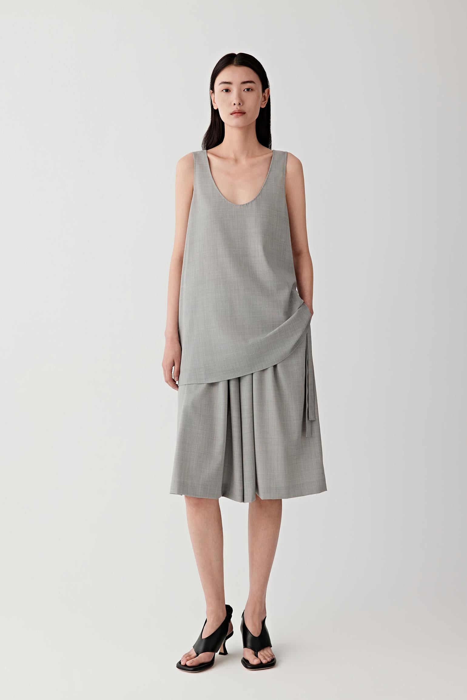 Woman wearing a light grey sleeveless wool top with a matching skirt, front view.
