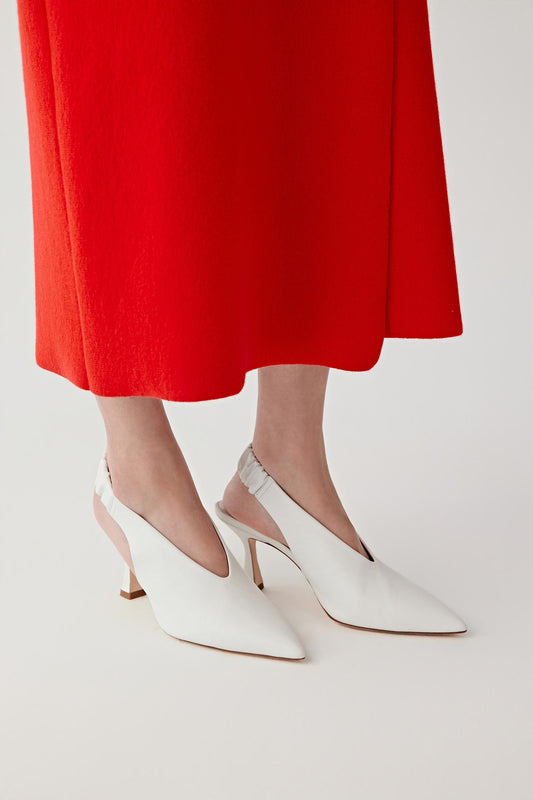 Side view of both feet showing the shoes worn in a natural standing position, emphasizing the curved mid heel, the wide upper and the slingback strap with gathered detail around the back of the foot