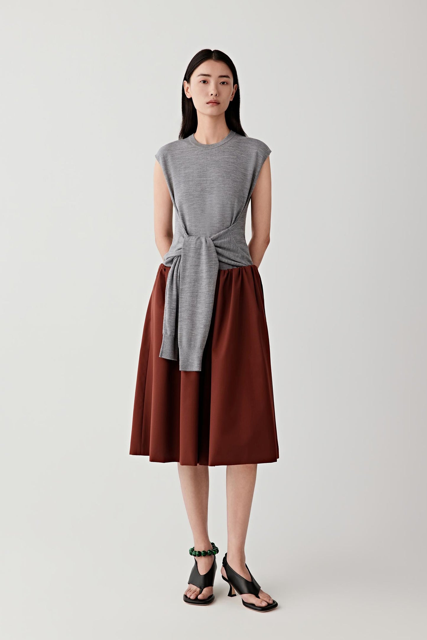 Woman wearing deep red-brown wool and silk shorts with a grey sleeveless top, front view.