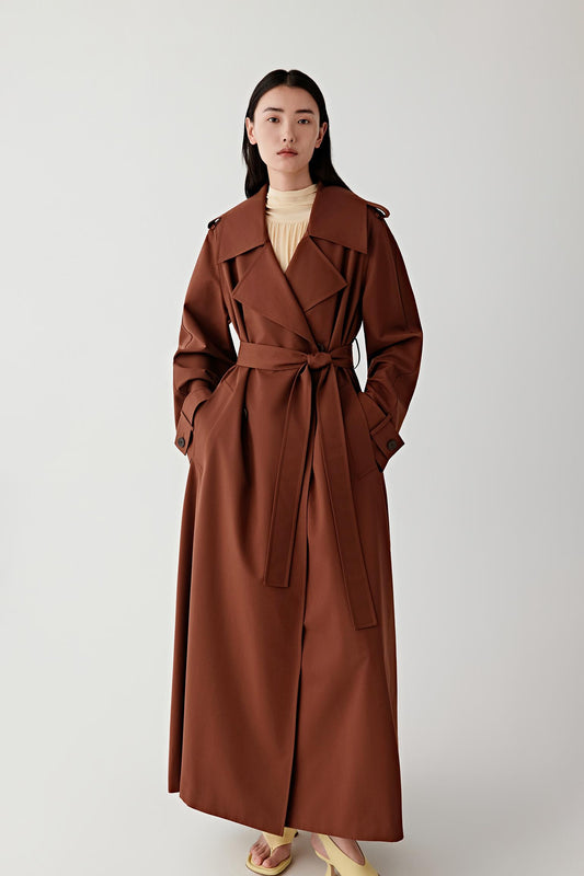 Woman wearing a brown trench coat against a white background