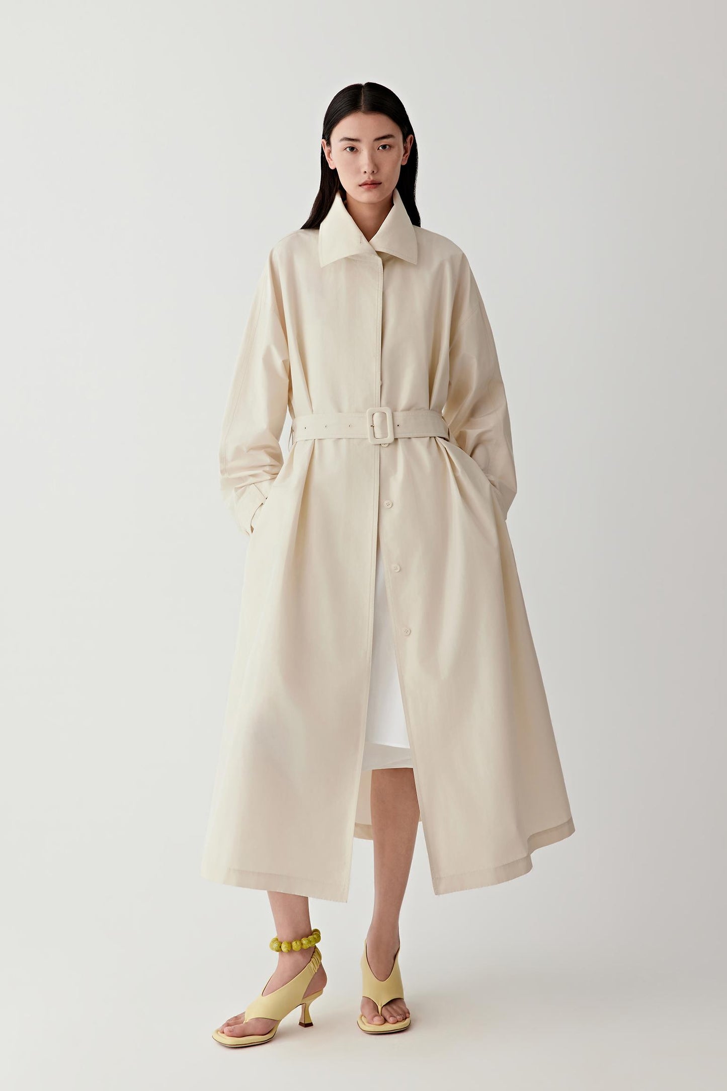 Woman wearing a beige trench coat on a white background