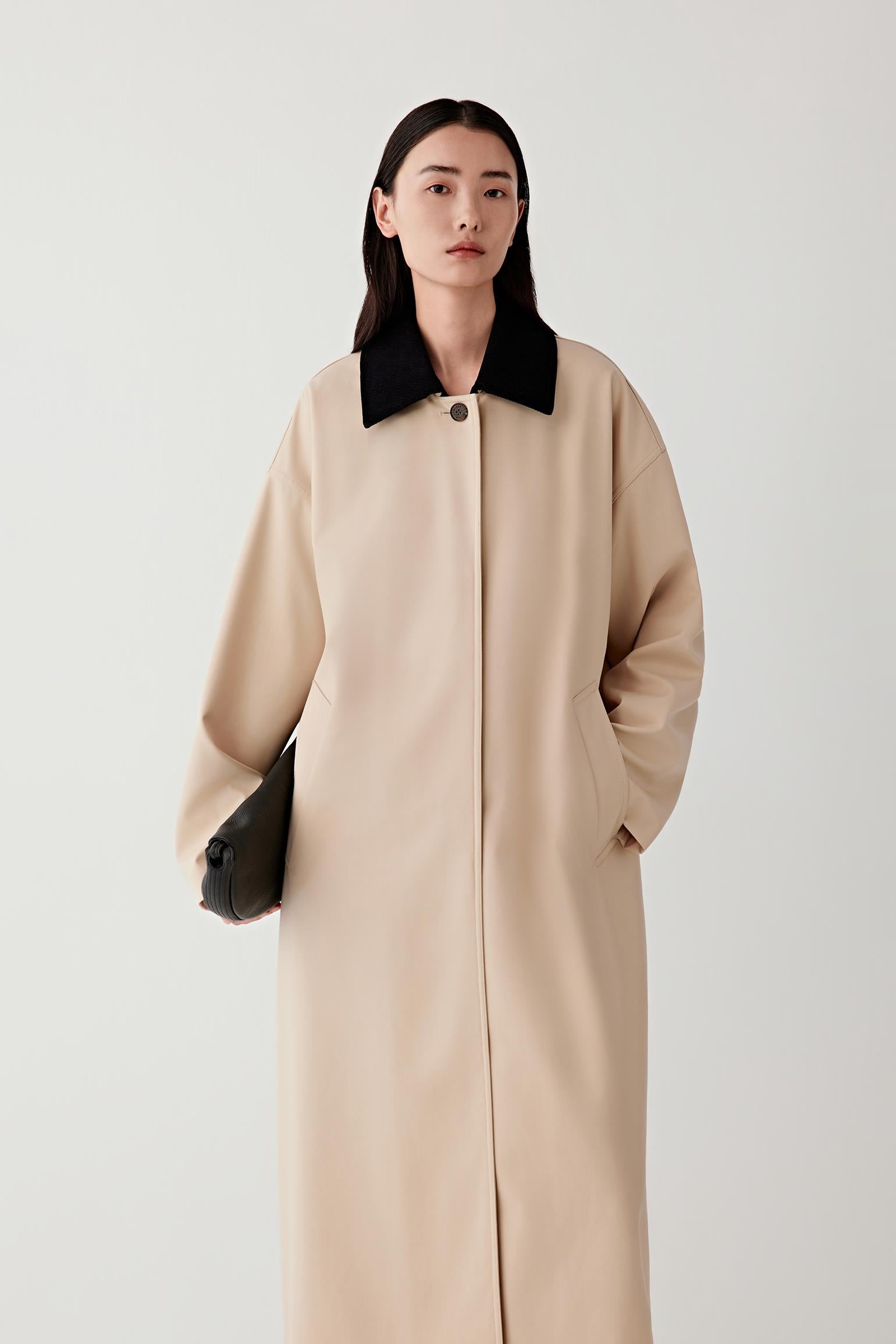 Woman wearing a beige coat with a black collar on a white background