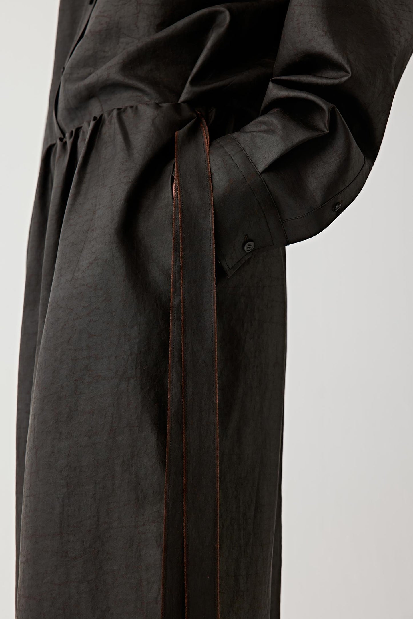 Close-up of the fabric surface showing the matte finish, tonal depth and irregular texture developed through the traditional mud-coating and sun-drying process. The image reveals the nuanced character and softly worn appearance of the silk surface.