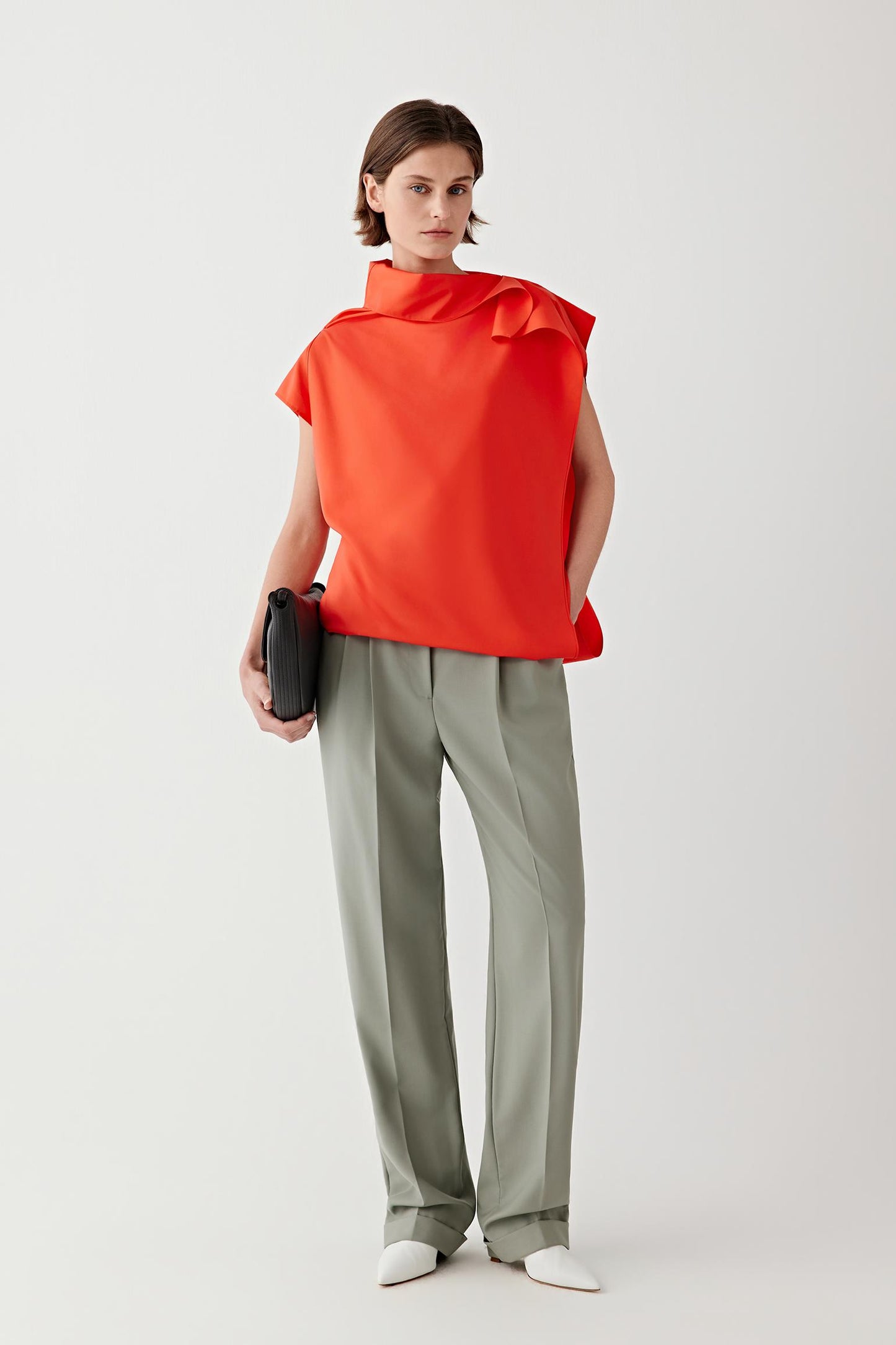 Full-length front view showing the blouse paired with tailored trousers, emphasizing the gently draped collar and fluid movement of the silk fabric