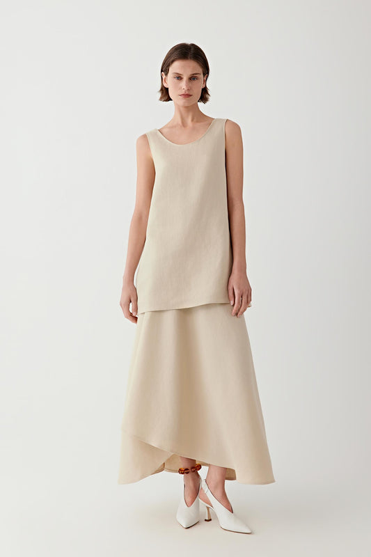 Woman wearing a sleeveless sand-colored blouse with a matching long skirt, full-length view.