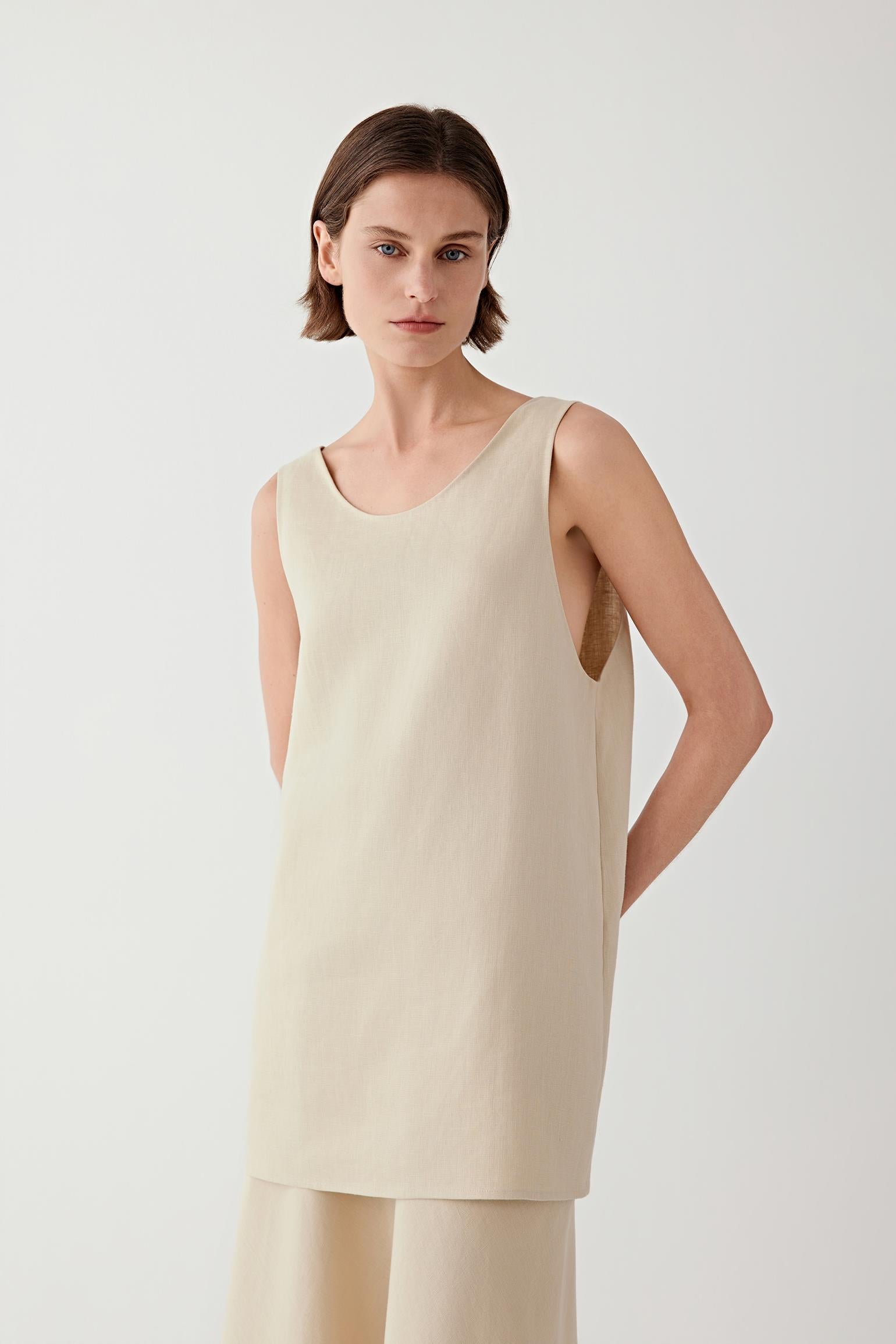 Three-quarter view of the sleeveless blouse showing the rounded neckline and fluid cut.