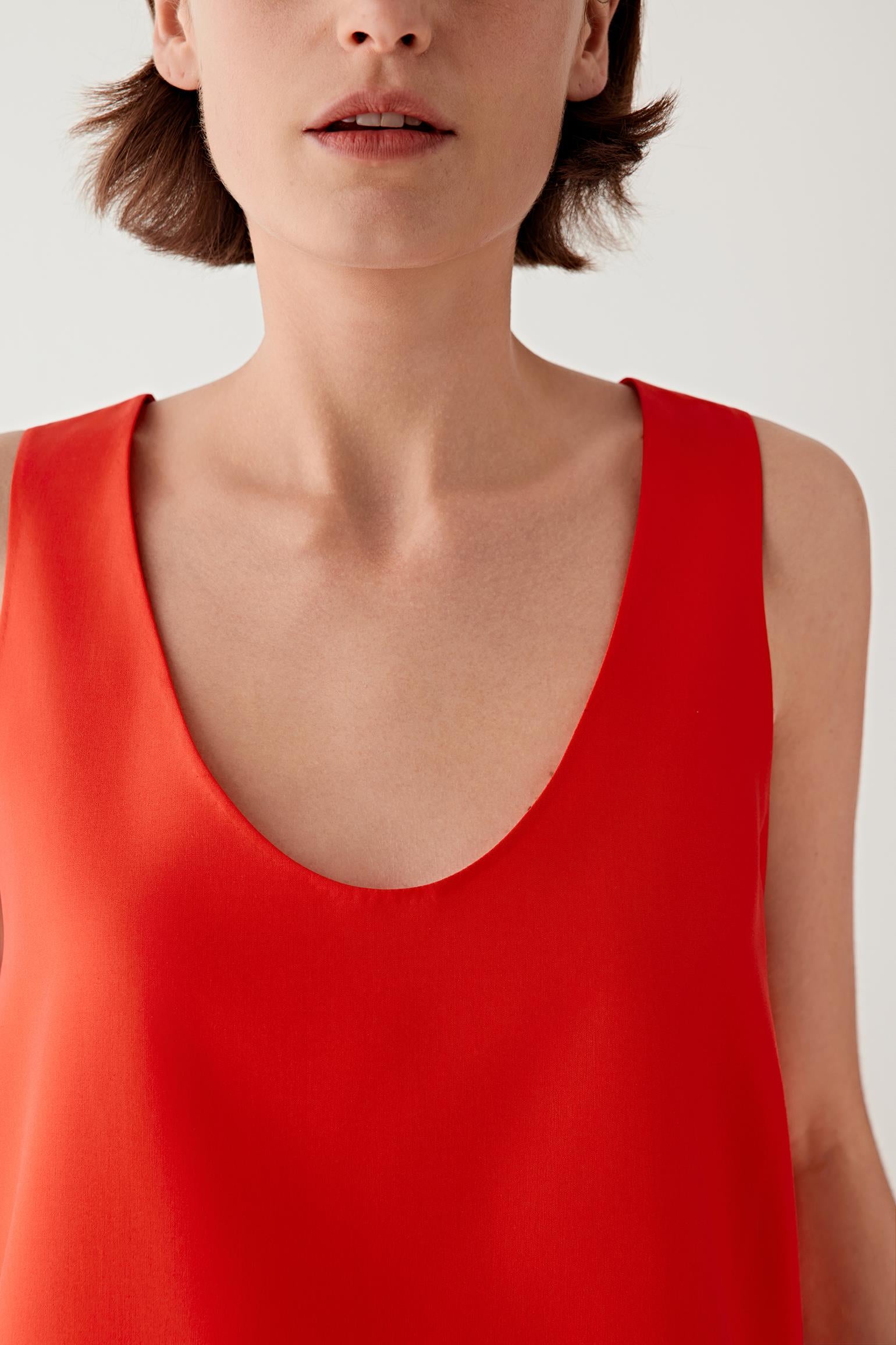 Close-up portrait focusing on the scoop neckline and upper construction, detailing the smooth woven surface and soft matte finish