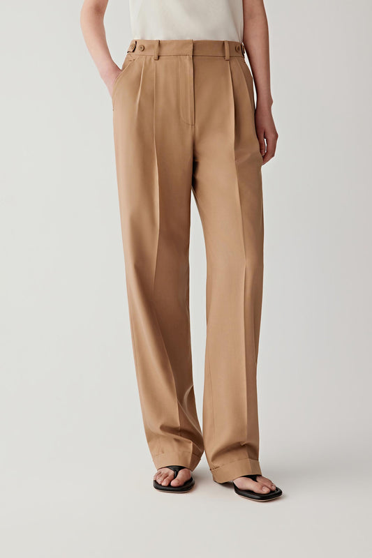 Front or three-quarter view emphasizing the straight-leg silhouette, tailored waistband and front pleats, showing the elongated line of the trousers