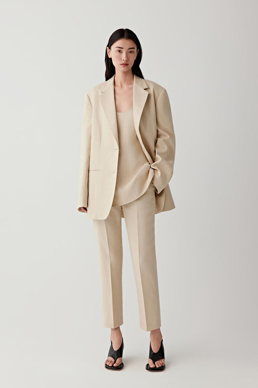 Woman wearing nude bootcut trousers with a matching blazer, full-length view.