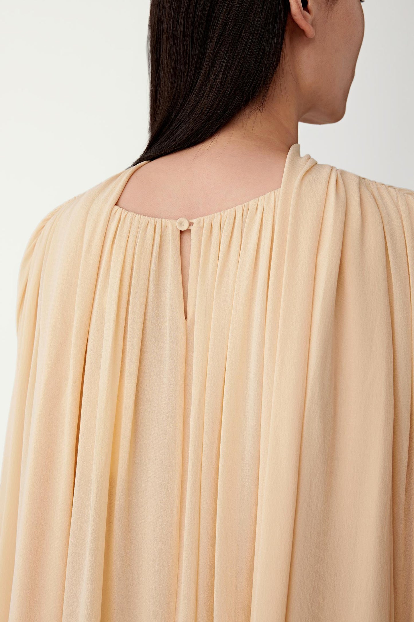 Close-up of the back and upper fabric, highlighting the gathered detailing, layered construction and the subtle depth created by the semi-sheer, matte silk surface
