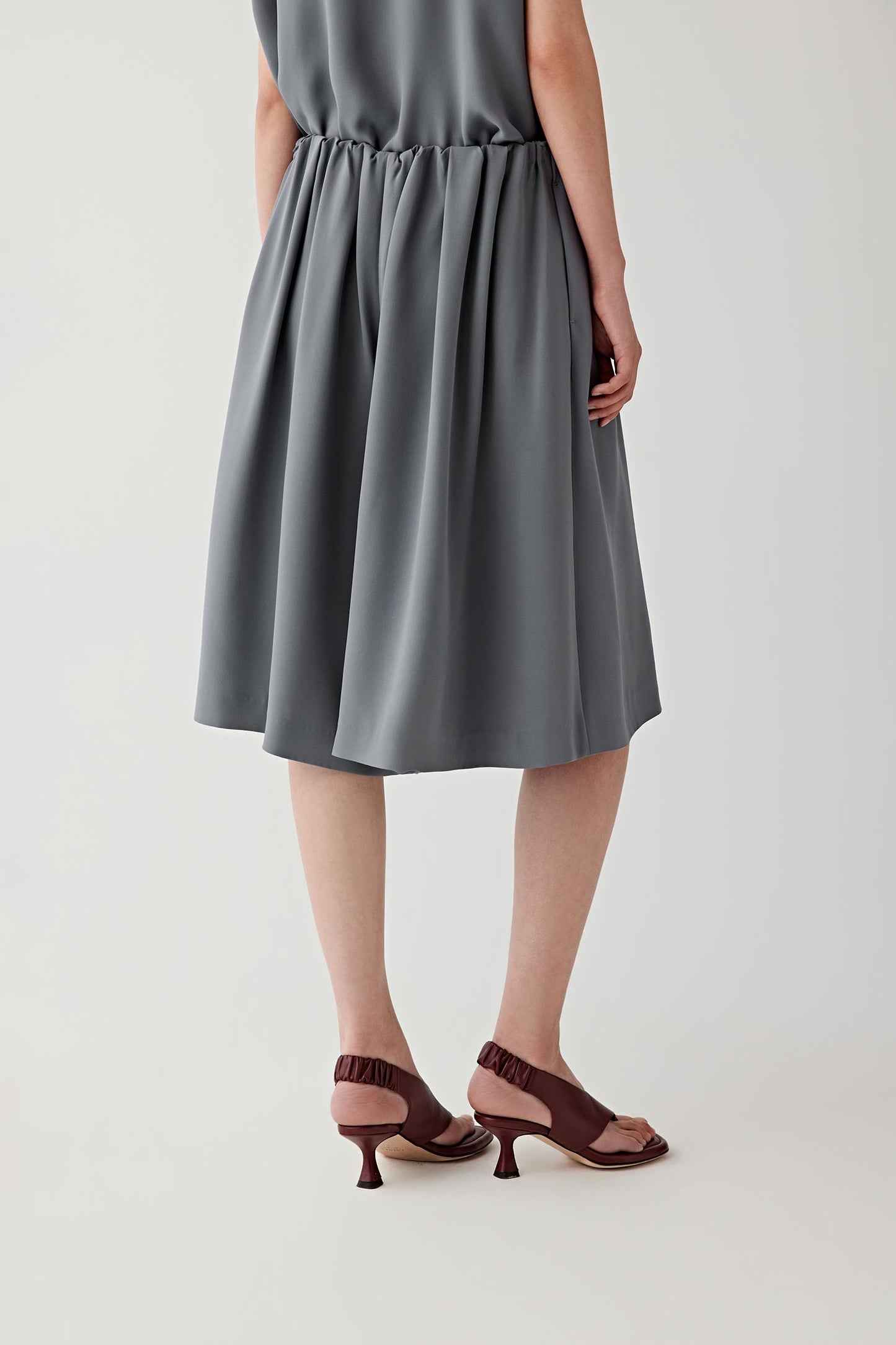 Side or back view emphasizing the fluidity of the silk crepe and the clean line of the shorts. The lightweight construction follows the body softly while maintaining balanced proportions.
