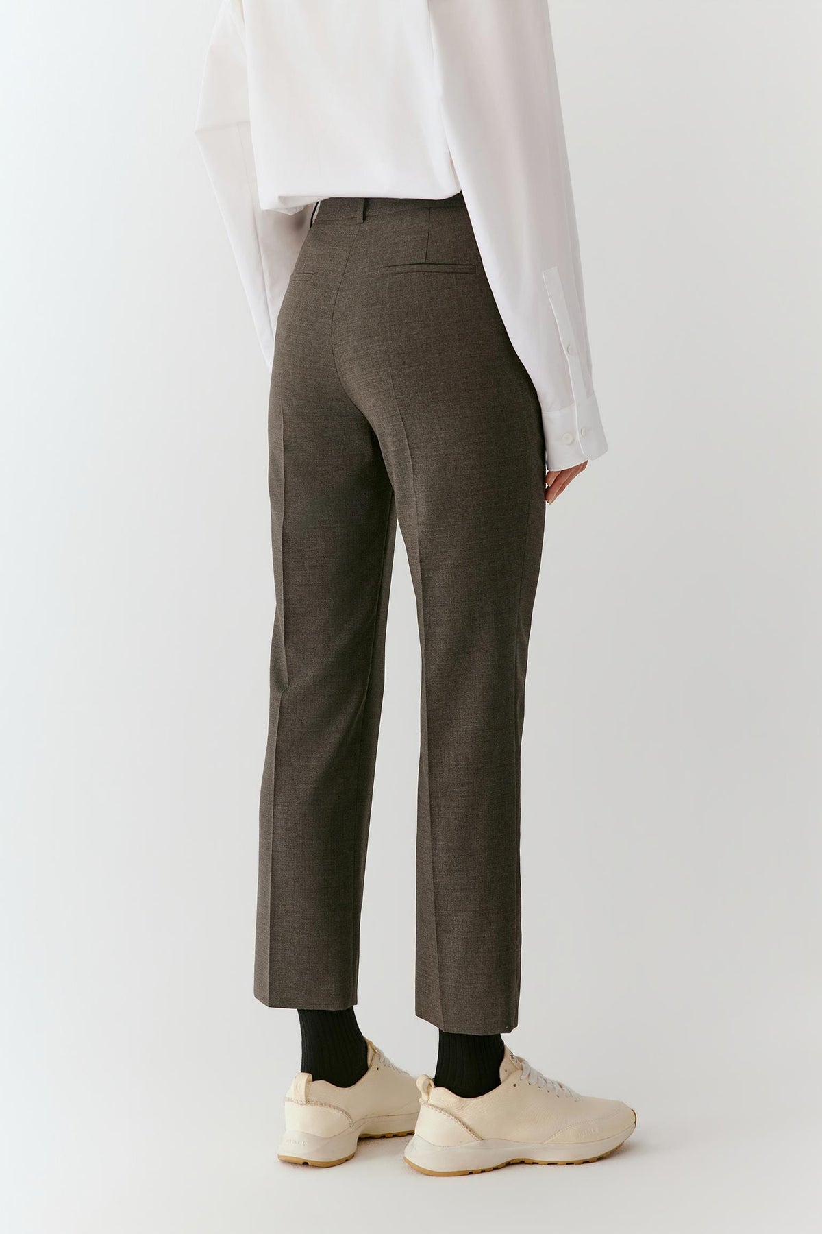 Three-quarter view highlighting the bootcut leg, pressed creases and clean tailoring of the grey melange wool.