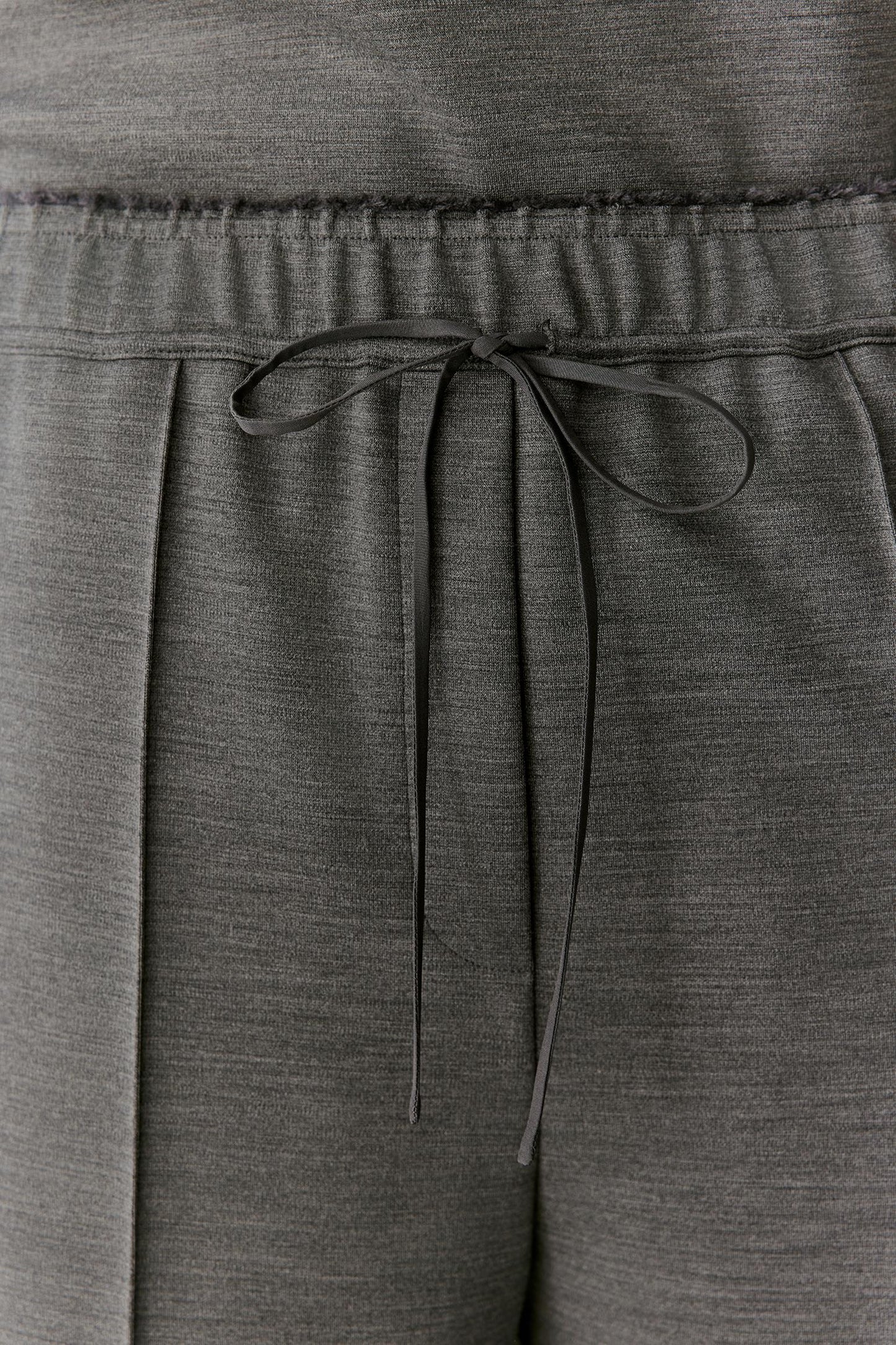 Close-up of dark gray heathered lounge pants showing the elastic waistband and drawstring tie.
