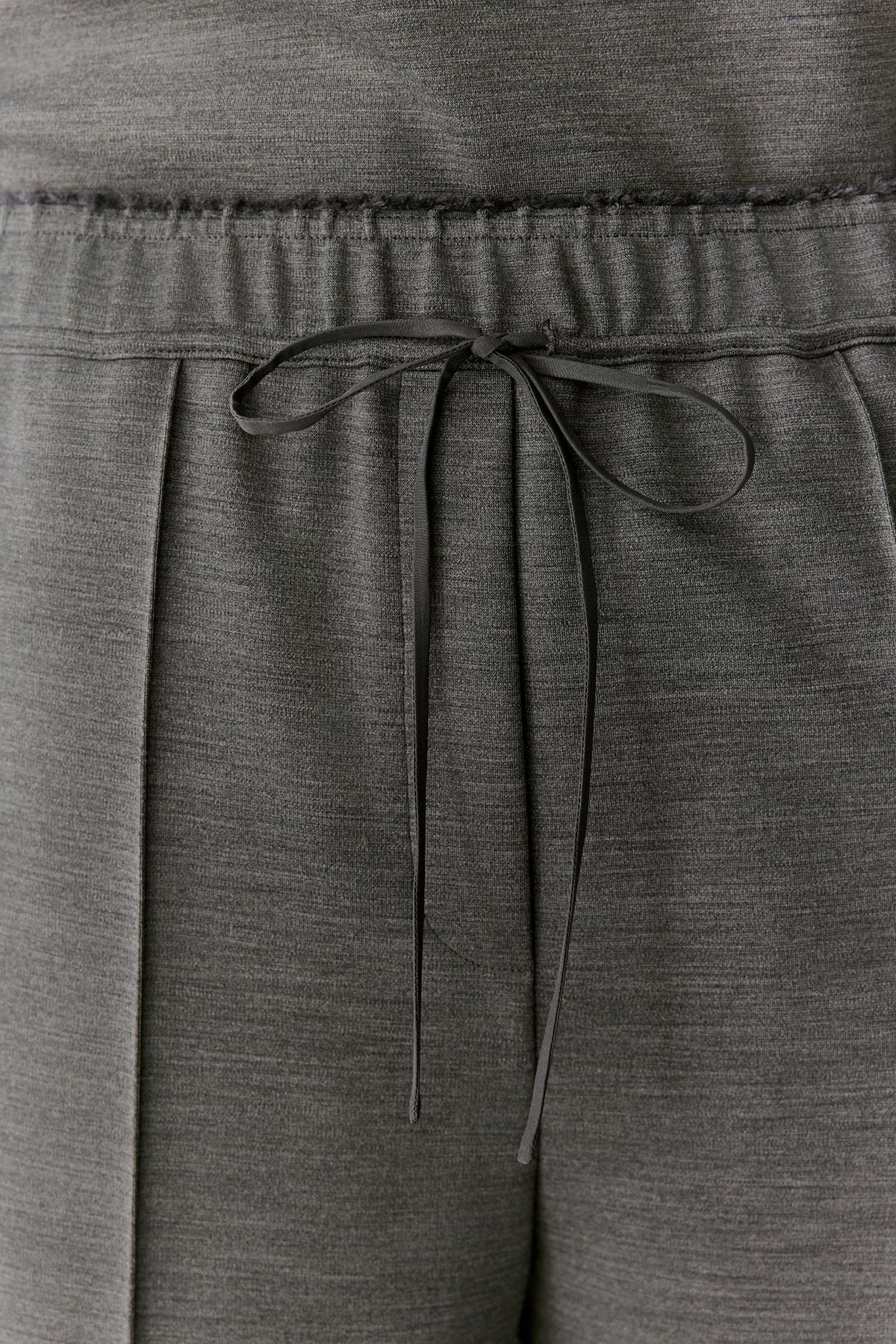 Close-up of dark gray heathered lounge pants showing the elastic waistband and drawstring tie.