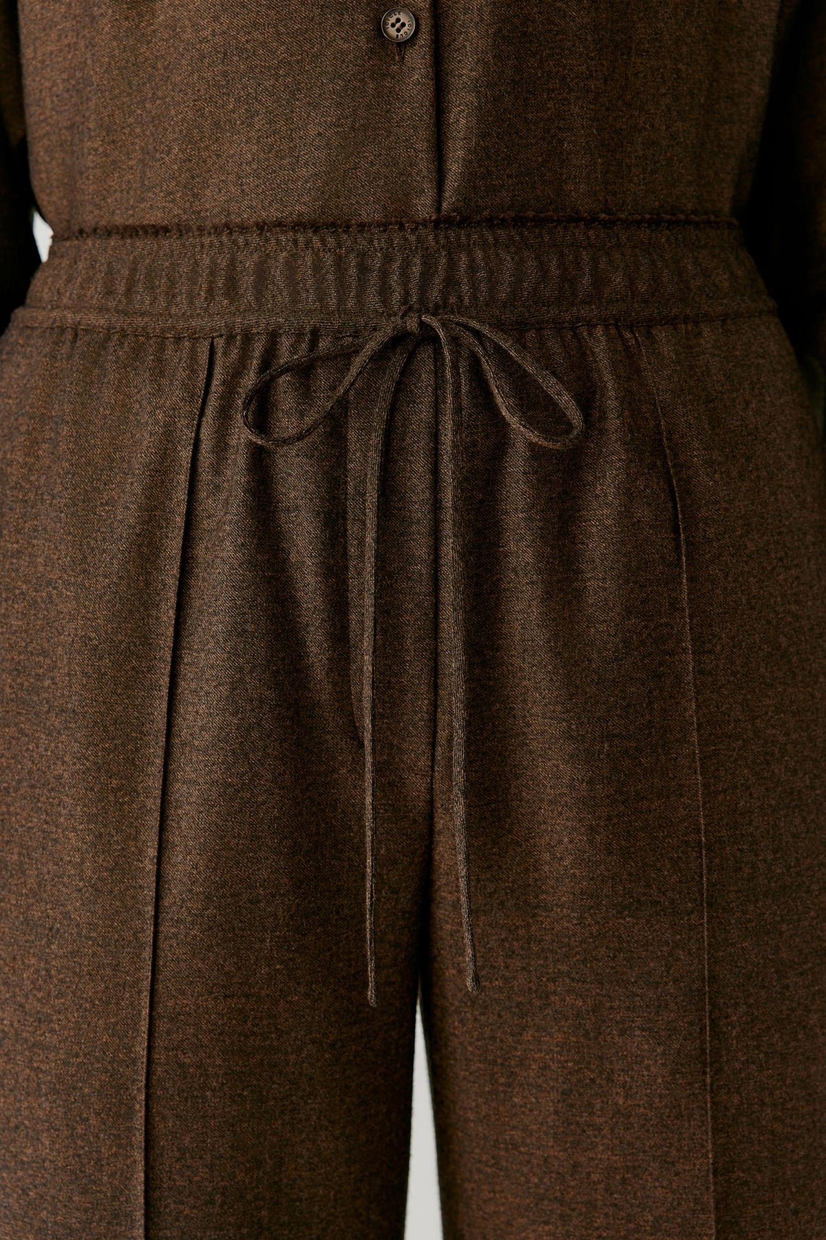 Close-up of the elasticated drawstring waistband of the brown wool flannel trousers.