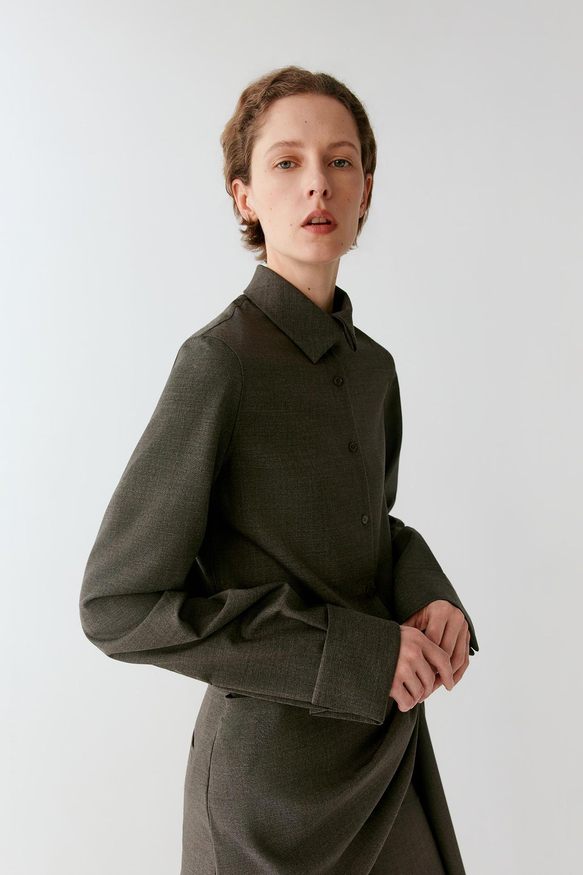 Closer view highlighting the straight hem, side slit and smooth grey melange wool surface.