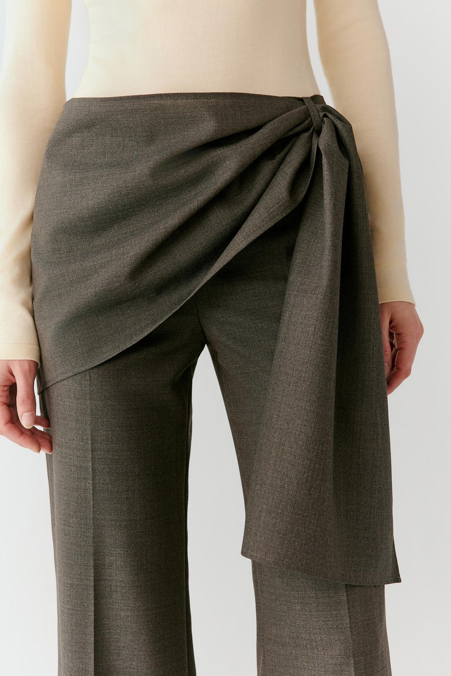 Close-up of the asymmetric waistband and overlapping front panel, showing the structured surface and clean finishing.