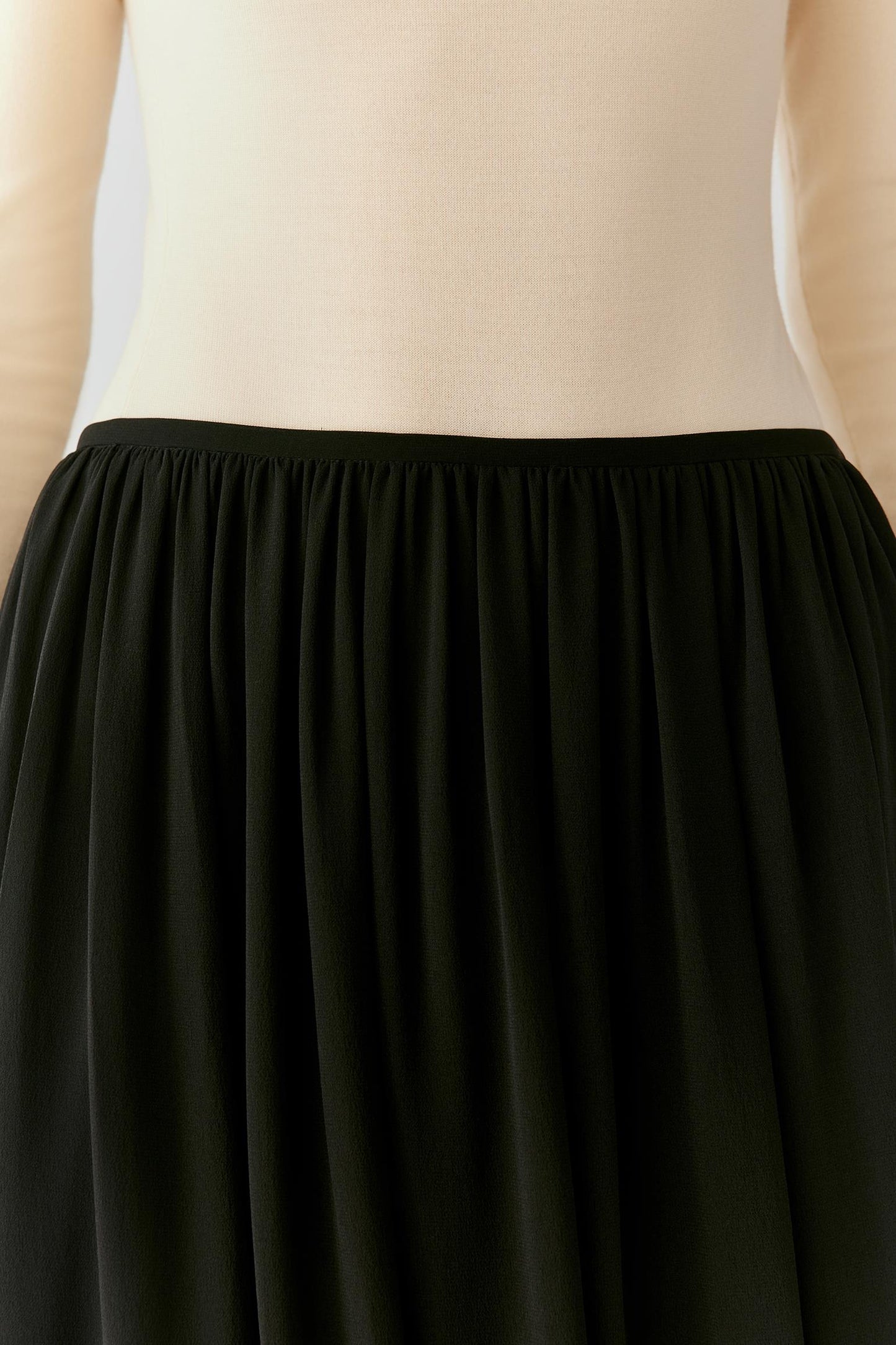 Close-up of the softly gathered elasticated waistband and black silk georgette texture.