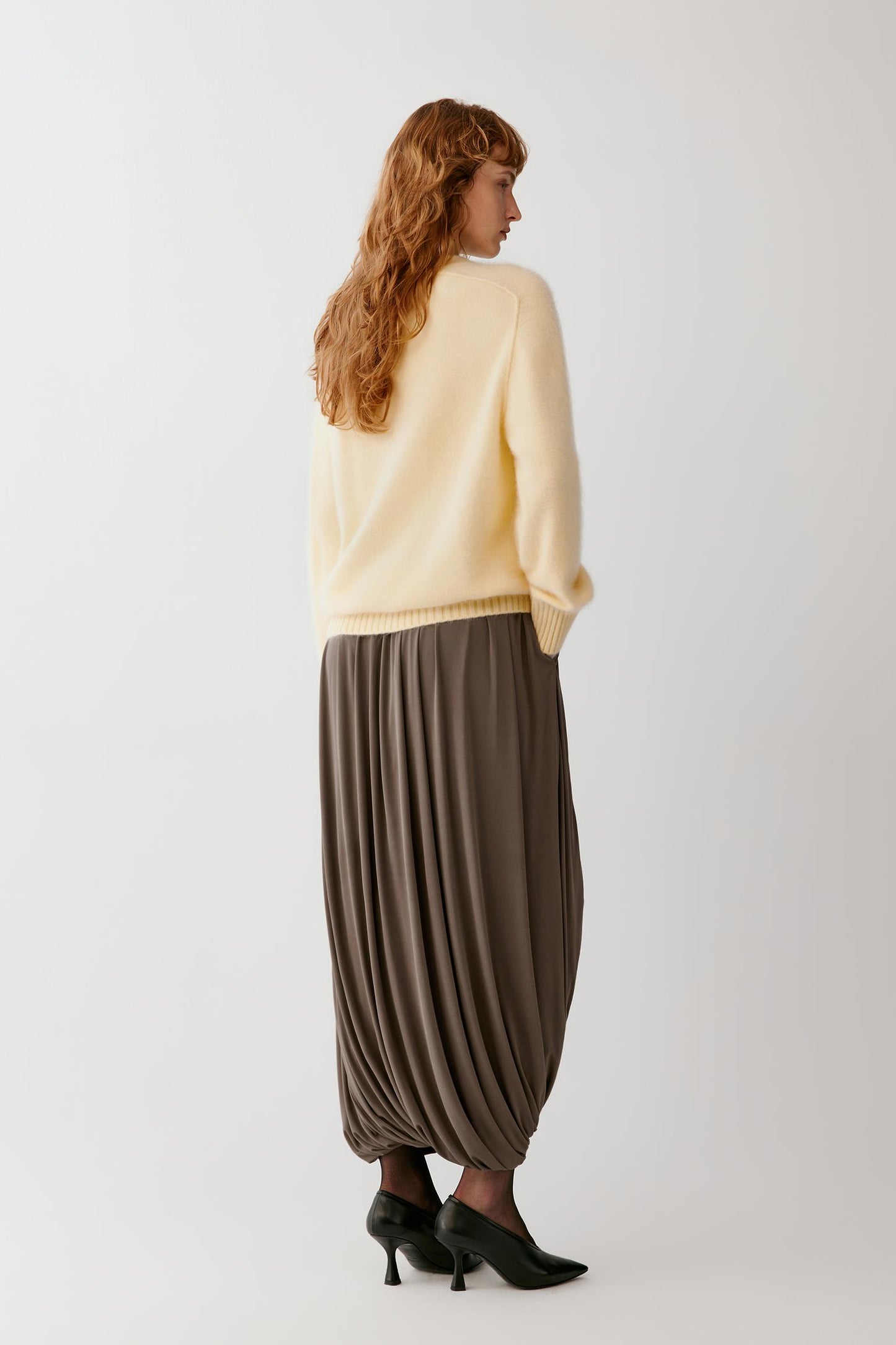 Back view highlighting the long cocoon shape, gathered construction and fluid fall of the silk jersey.