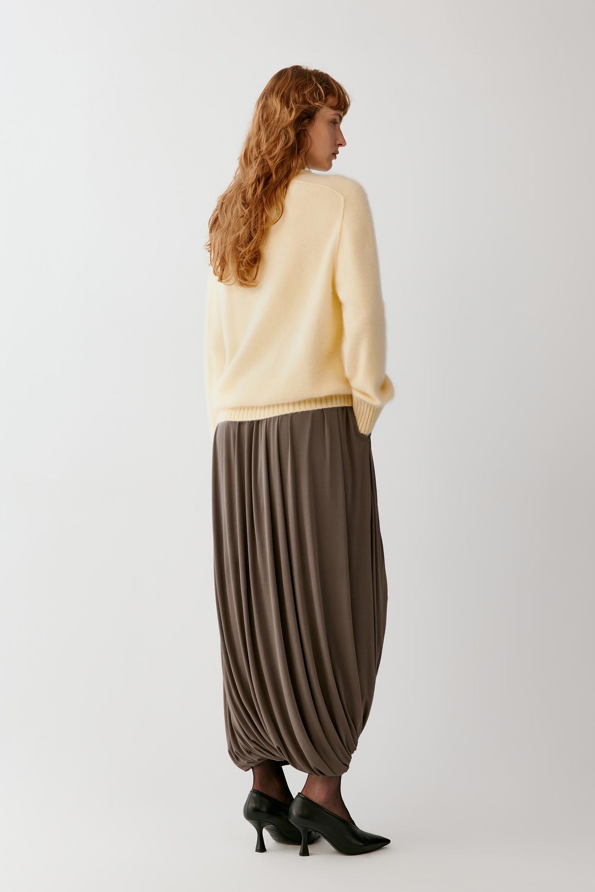 Back view highlighting the long cocoon shape, gathered construction and fluid fall of the silk jersey.