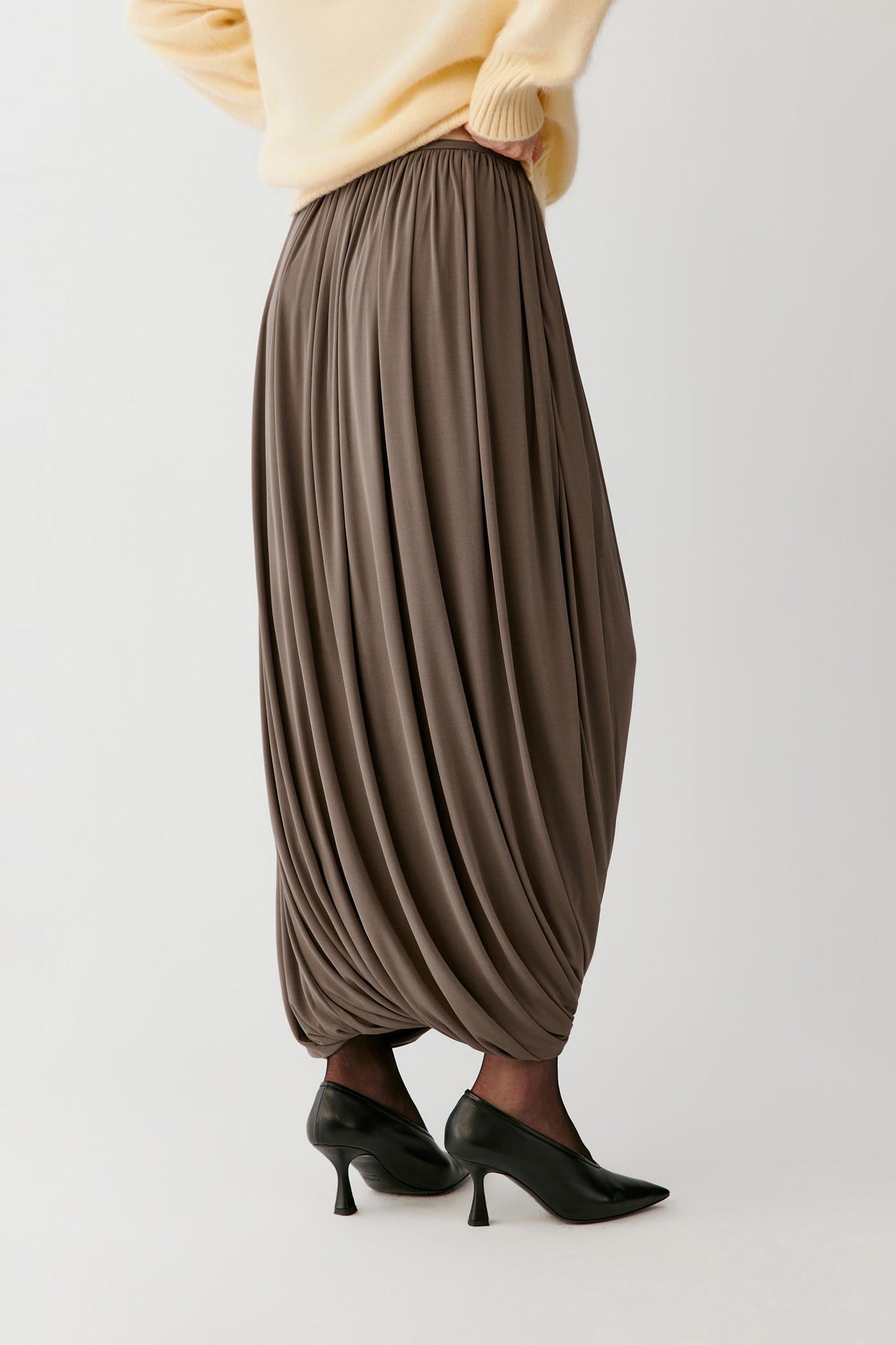 Three-quarter view showing the sculpted volume, soft folds and smooth surface of the taupe fabric.