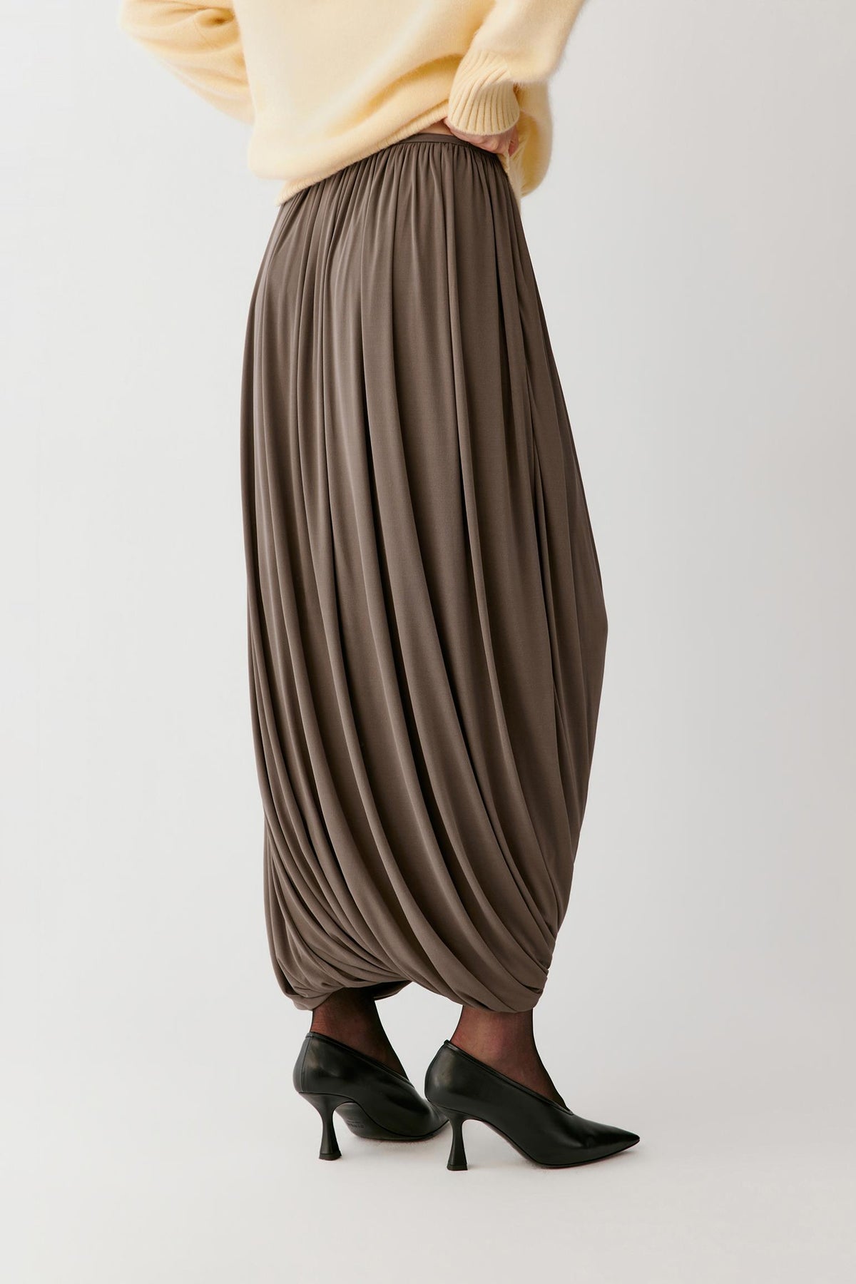 Three-quarter view showing the sculpted volume, soft folds and smooth surface of the taupe fabric.