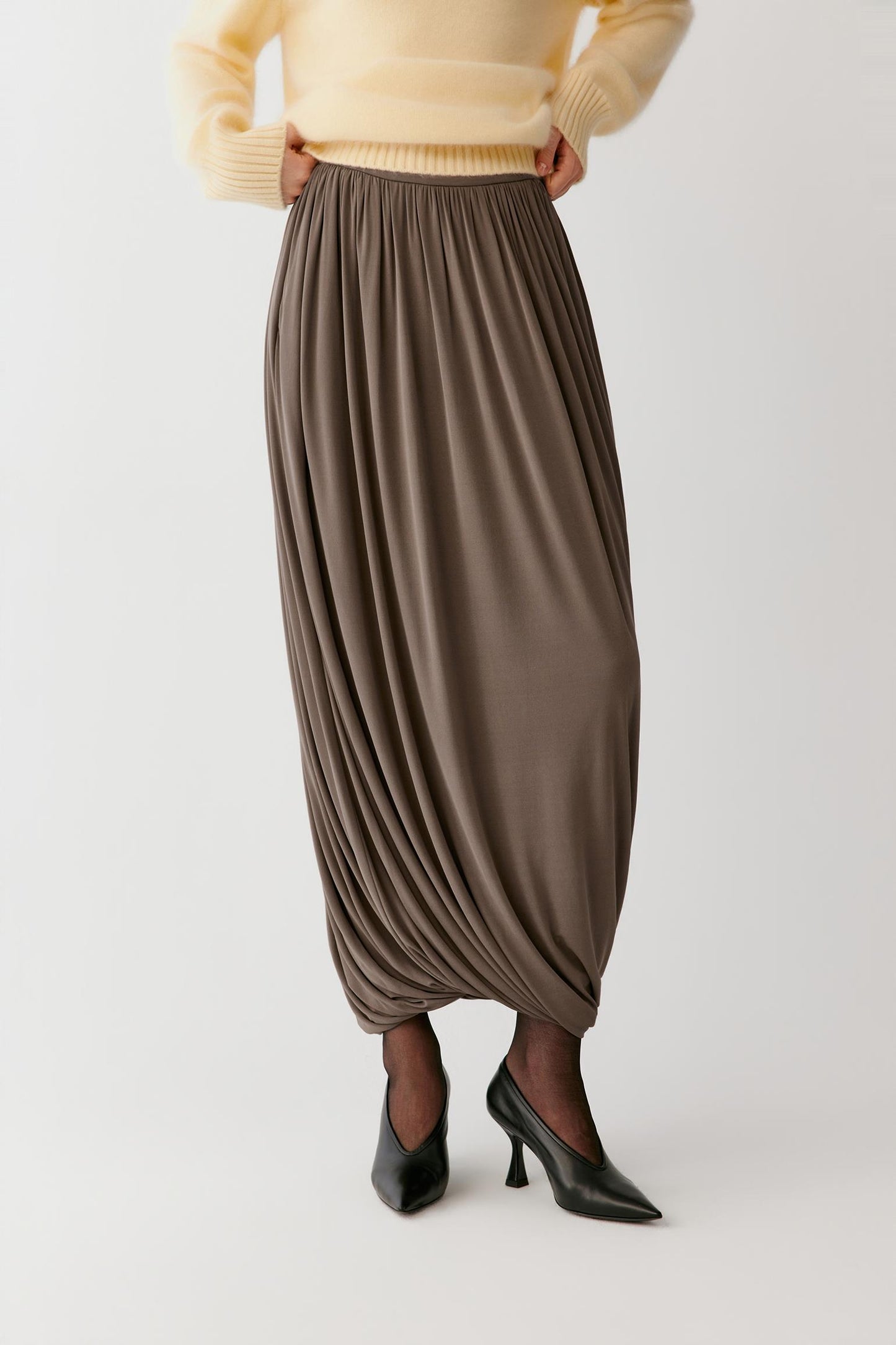 Full-length front view emphasizing the elasticated gathered waistband, softly rounded volume and gathered hem.