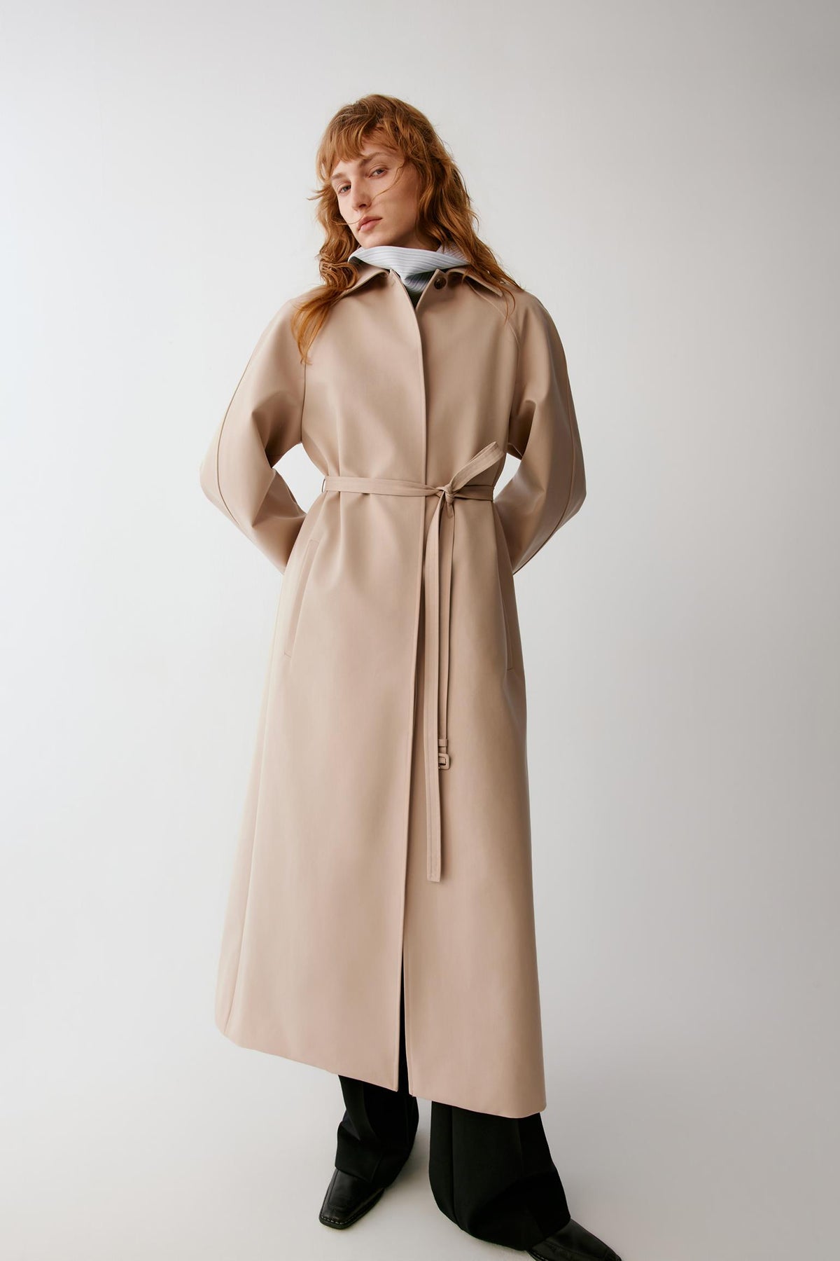 Full-length front view emphasizing the concealed single-breasted fastening, belted waist and clean drape of the fabric.