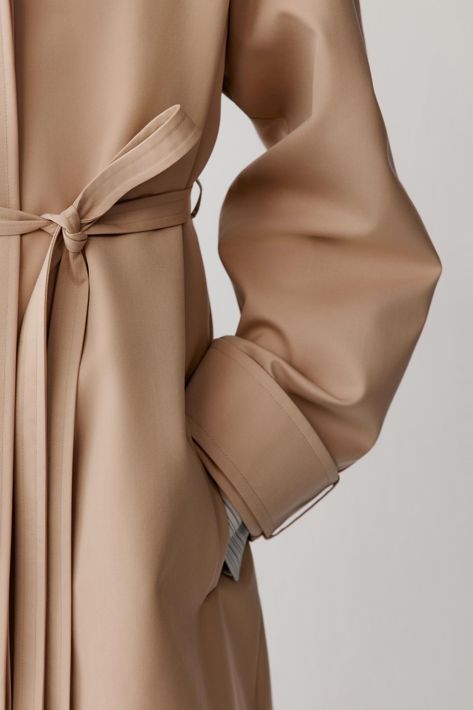 Close-up highlighting the adjustable belt, welt pocket and clean finishing at the waist.