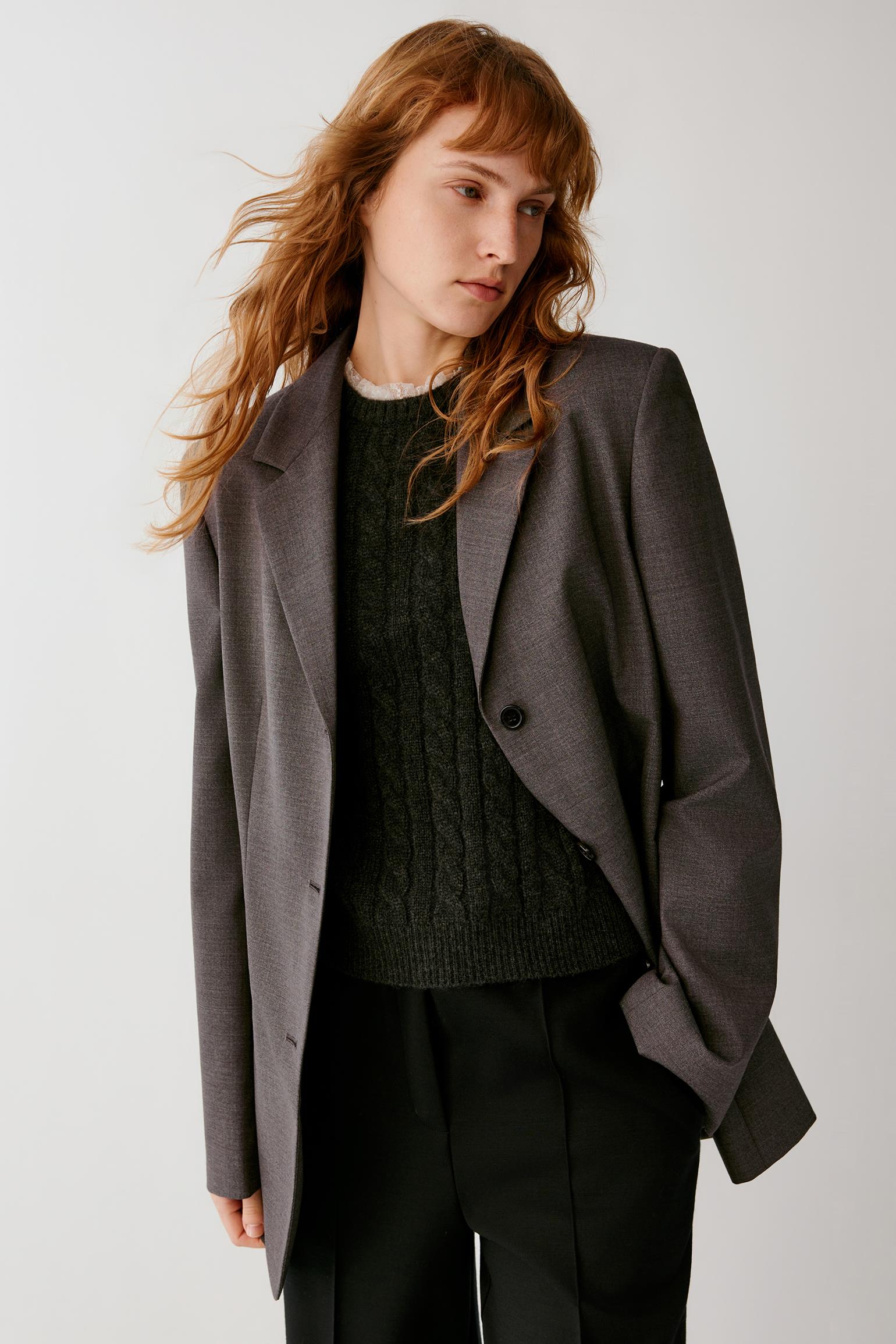 Side view showing the straight silhouette and fluid drape of the grey melange wool blazer.