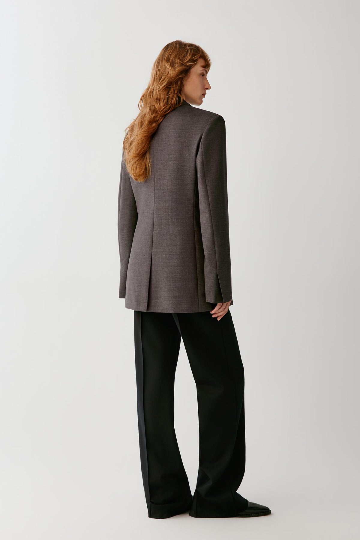 Three-quarter view highlighting the notched collar, welt pockets and structured wool suiting fabric.