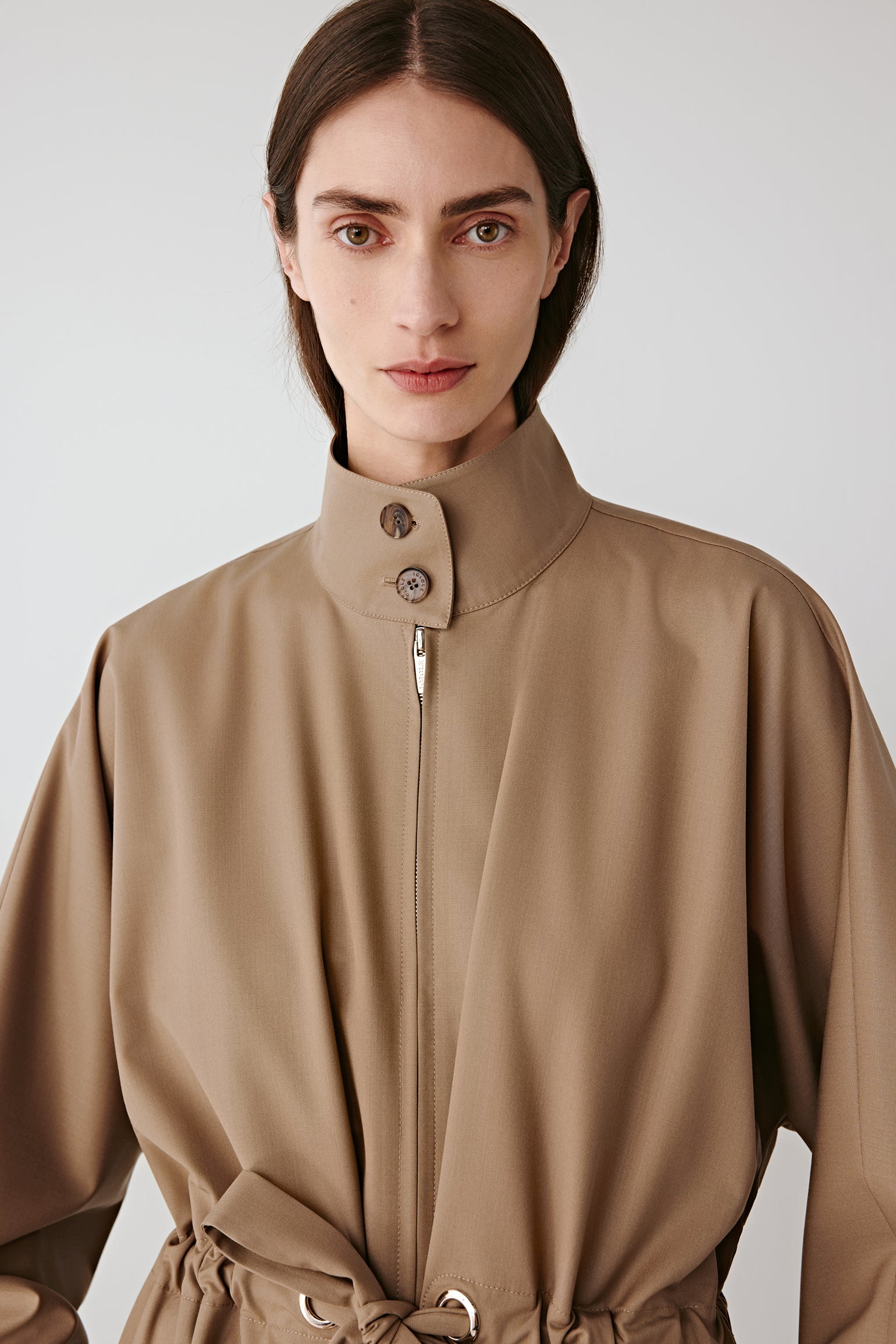 Close-up portrait of the upper part of the beige coat, featuring the shirt collar and structured shoulders.