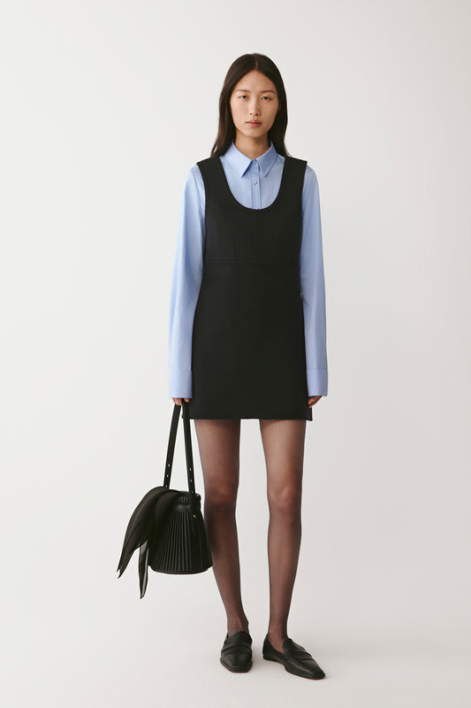 Front view of the black double-faced wool cashmere short dress worn over a blue shirt, showing the structured fit.
