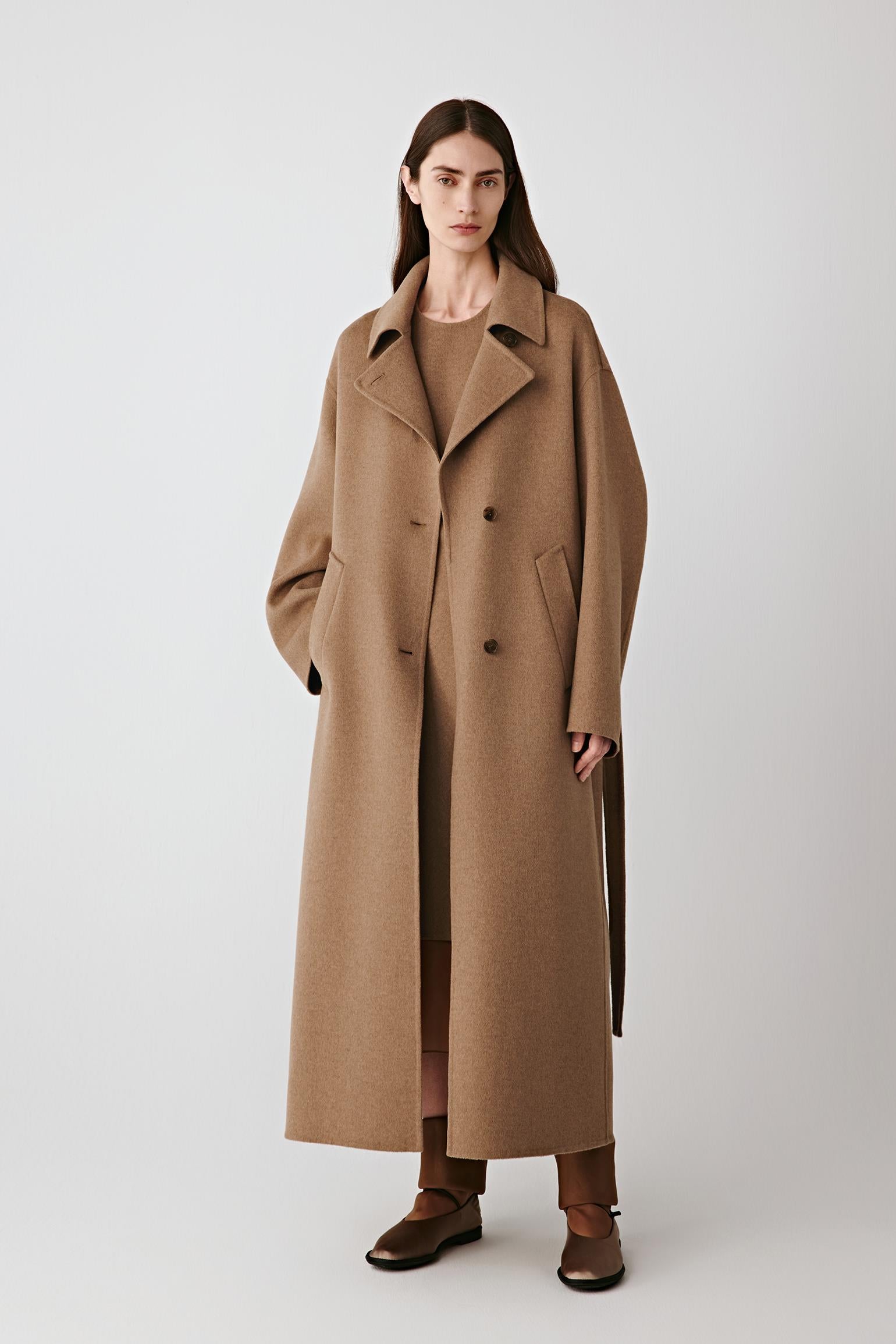 Full-length front view of the long camel coat in double-faced worsted wool and silk, showing the enveloping silhouette and clean lines.