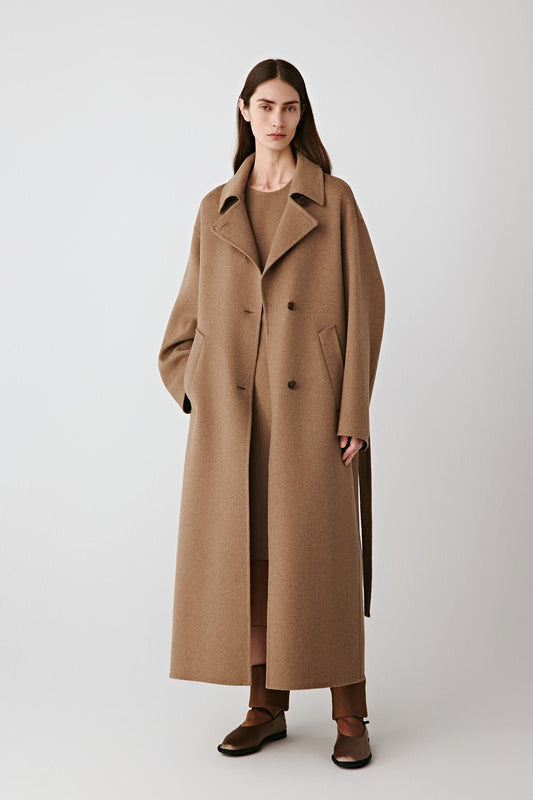 Full-length front view of the long camel coat in double-faced worsted wool and silk, showing the enveloping silhouette and clean lines.