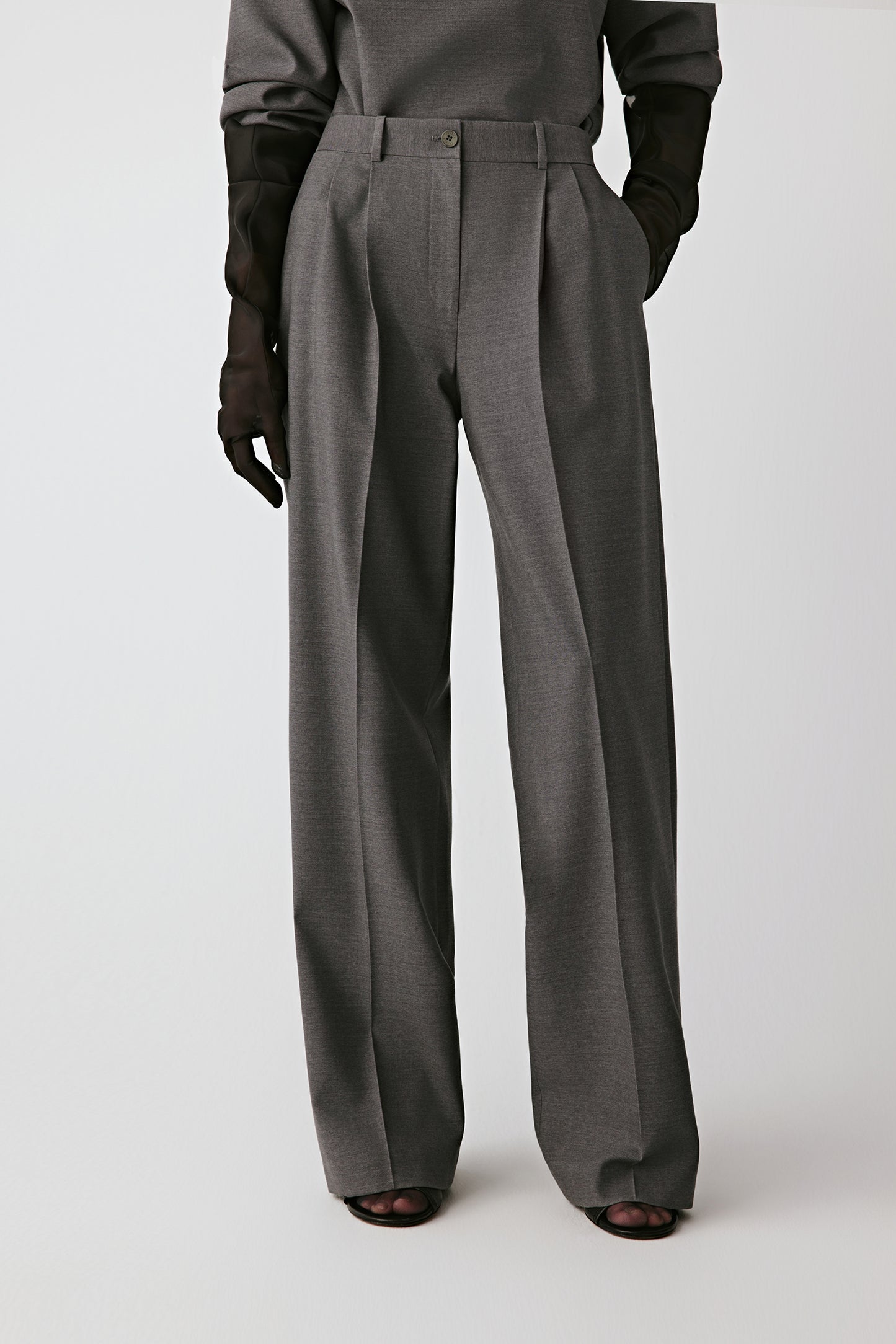 Three-quarter front view showing the sharp pleats and belted waistband.